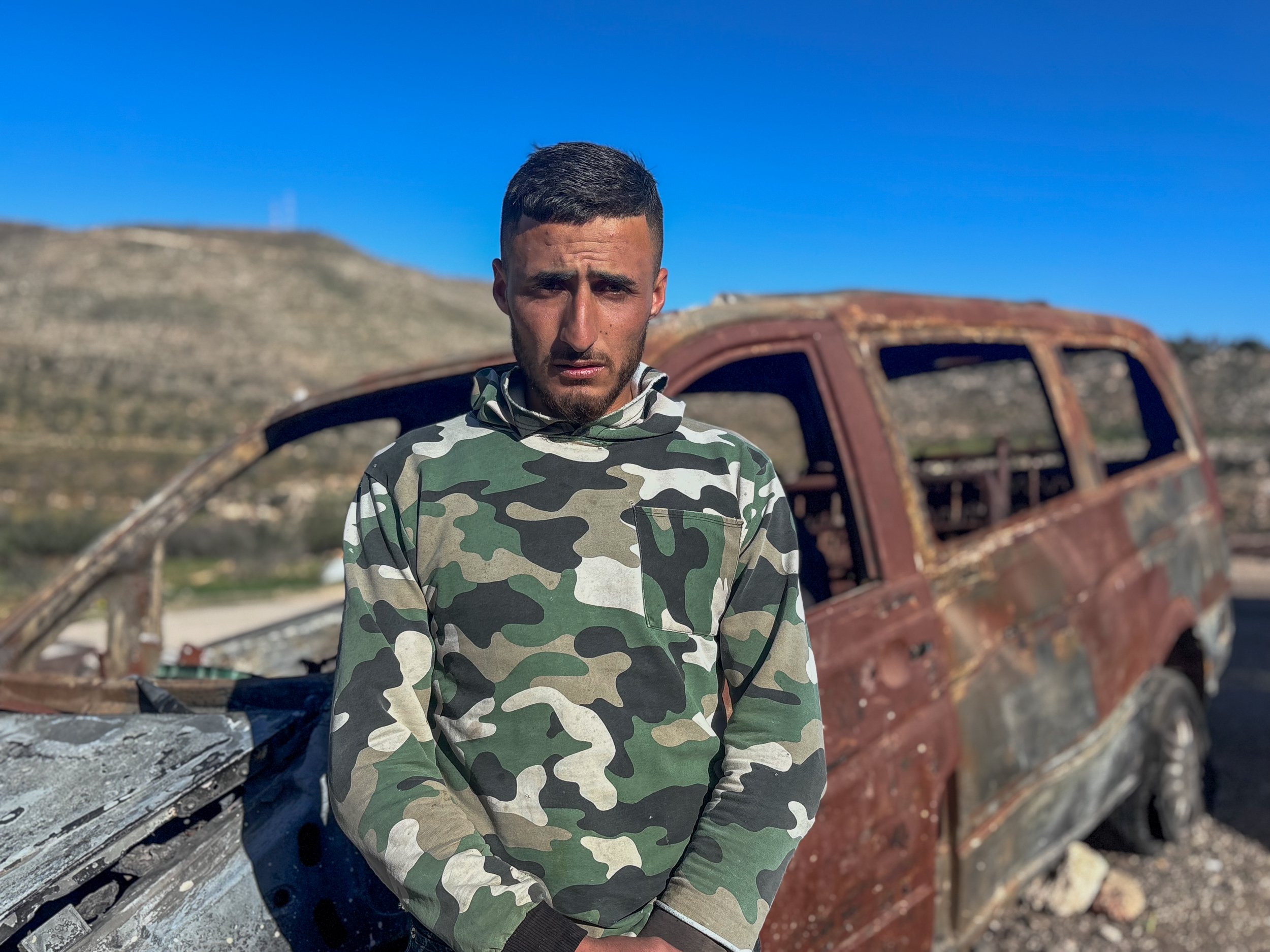 Thabet Masallam in front of car torched by illegal Israeli settlers