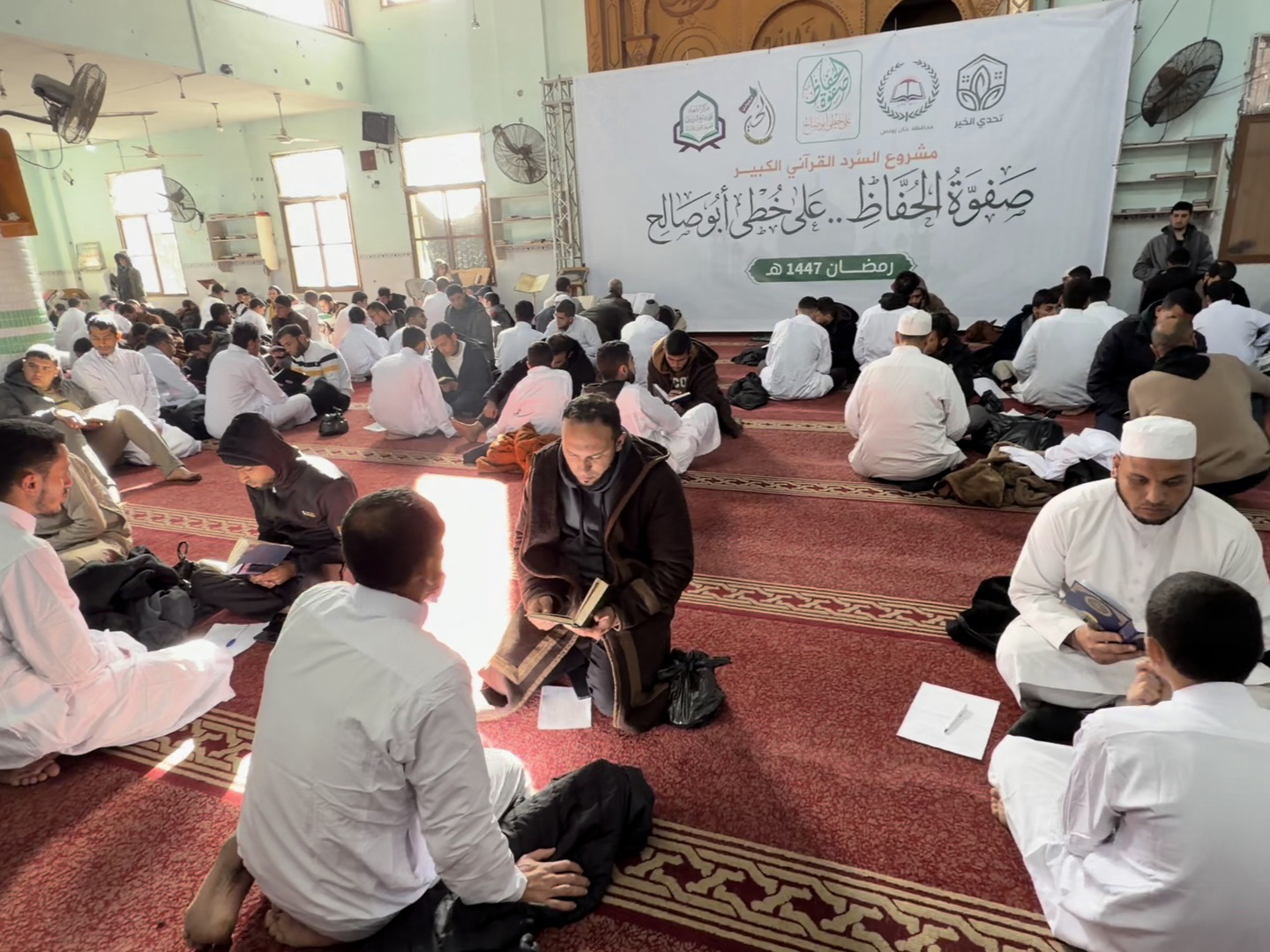 Crowd of keepers sitting in the mosque hall reciting the Qur'an by heart