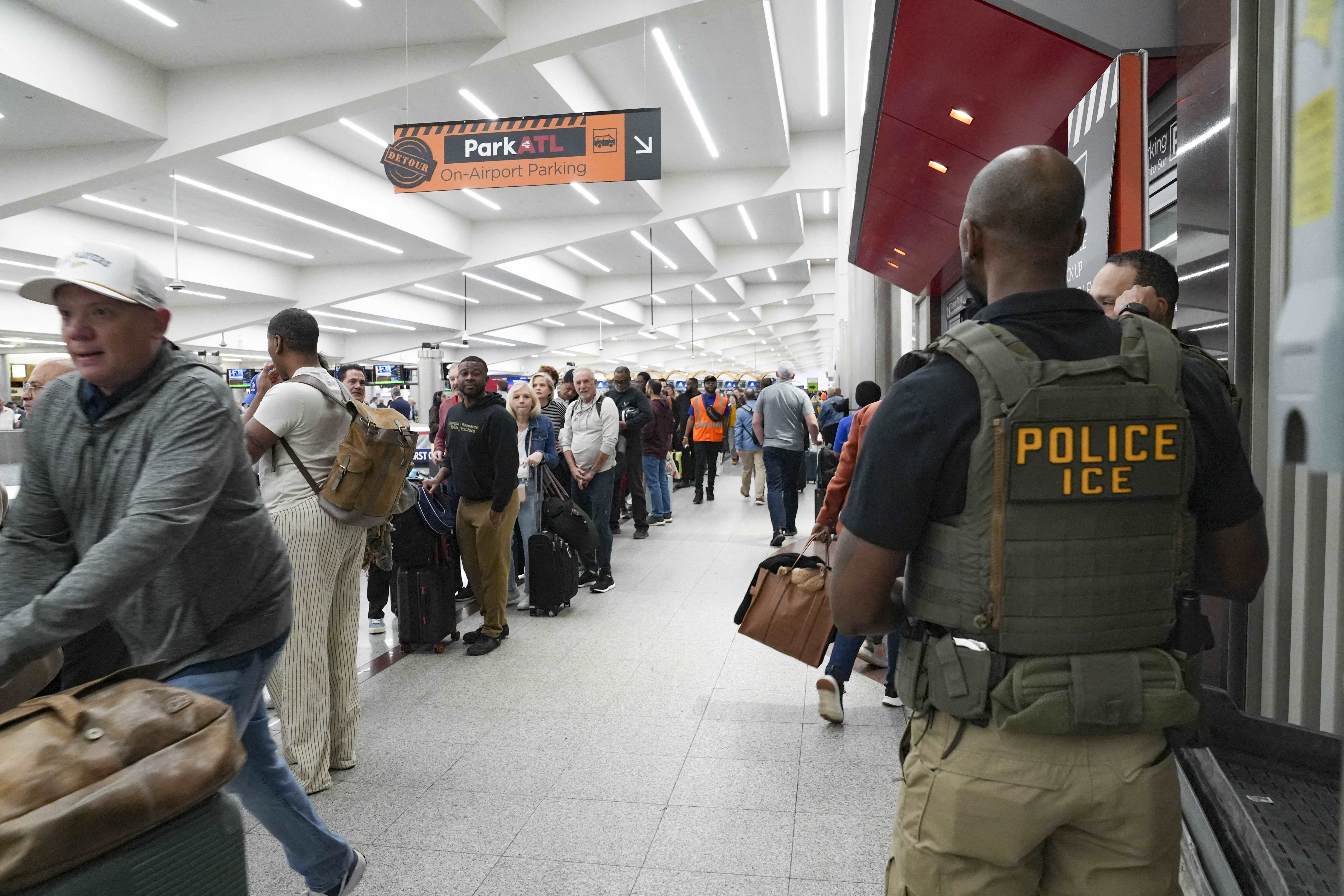 ATLANTA, GEORGIA - MARCH 23: Ice agents look on as travelers stand in long lines at Atlanta Hartsfield-Jackson International Airport on March 23, 2026 in Atlanta, Georgia. The travel disruptions continue as hundreds of TSA agents quit or work without pay during a partial government shutdown. U.S. President Donald Trump said ICE agents will be deployed to U.S. airports on Monday, with border czar Tom Homan in charge of the effort. Megan Varner/Getty Images/AFP (Photo by Megan Varner / GETTY IMAGES NORTH AMERICA / Getty Images via AFP)