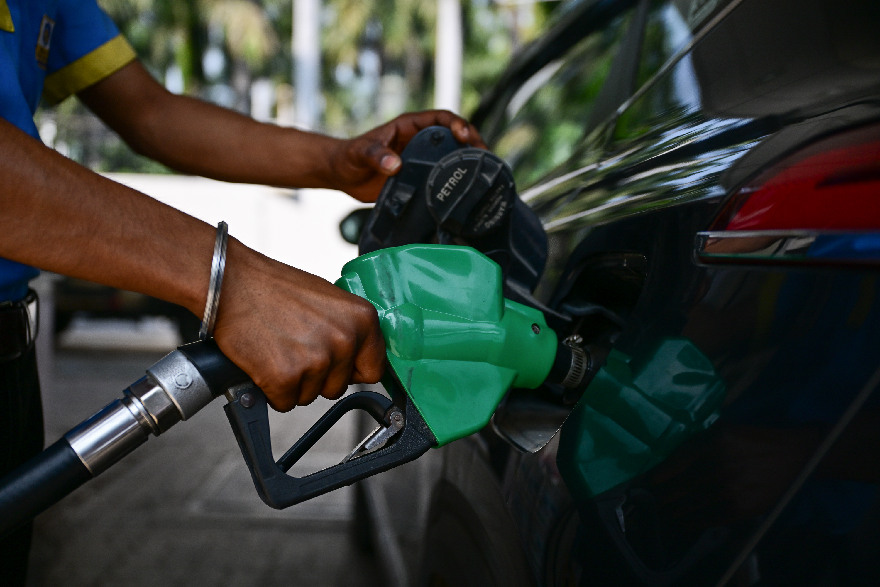 A fuel pump attendant refuels a car in New Delhi, India