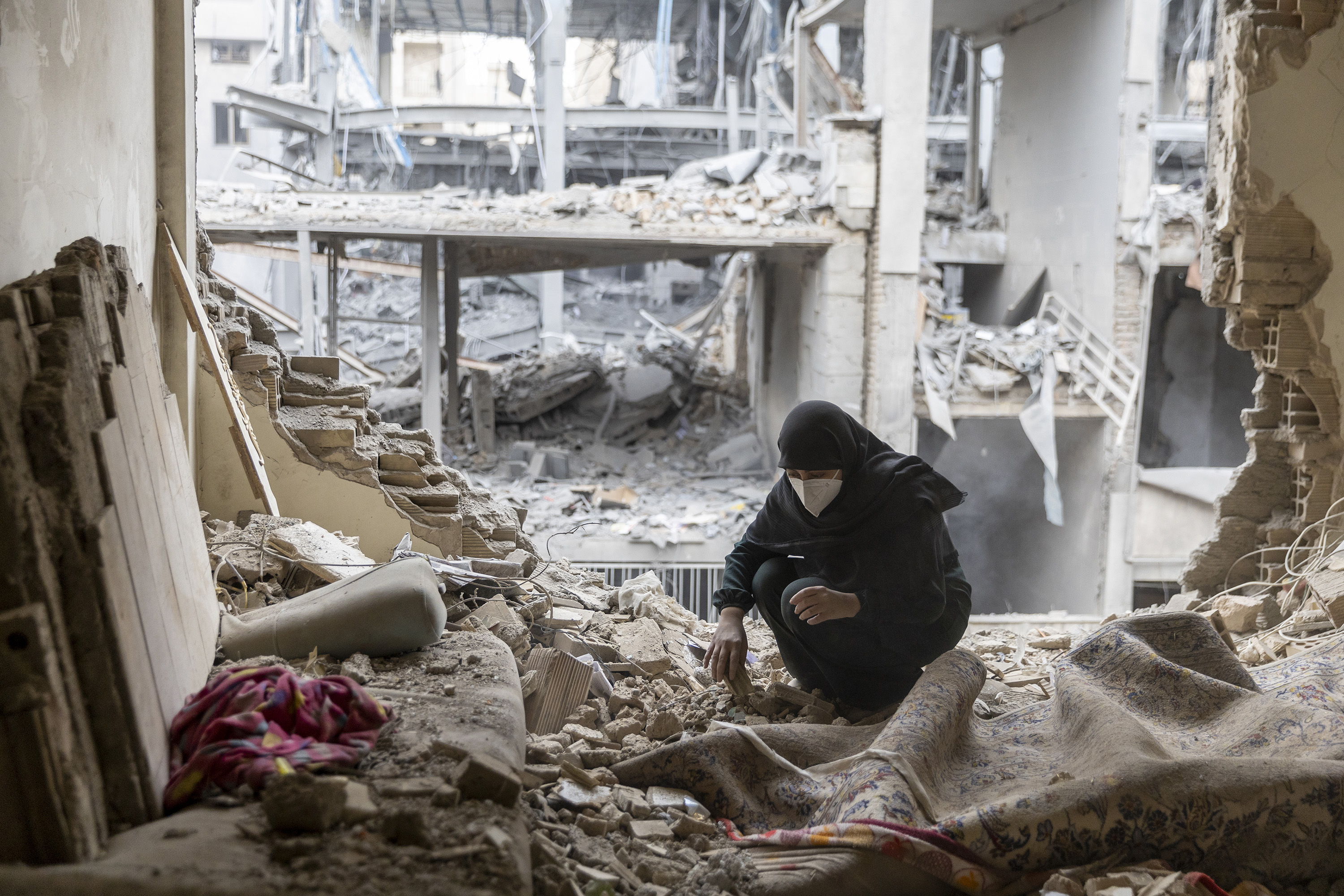 TEHRAN, IRAN - MARCH 15: A woman sifts through the rubble in her house in the Beryanak District after it was damaged by missile attacks two days before, on March 15, 2026 in Tehran, Iran. The United States and Israel continued their joint attack on Iran that began on February 28. Iran retaliated by firing waves of missiles and drones at Israel, and targeting U.S. allies in the region. (Photo by Majid Saeedi/Getty Images)