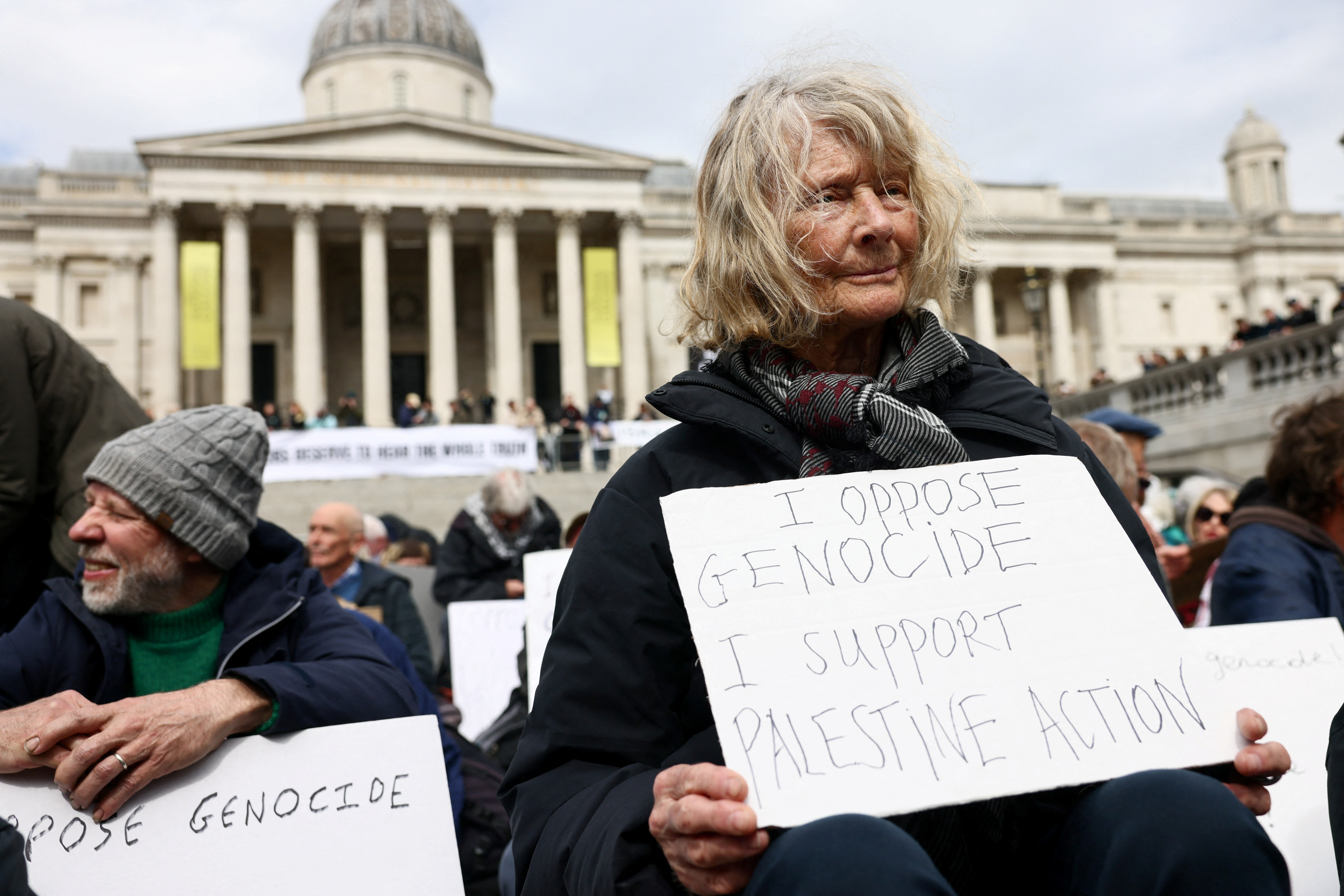 Protesters hold signs at 'Everyone Day', a mass vigil and sign-holding event in Trafalgar Square organised by Defend Our Juries to demand the lifting of the ban on Palestine Action, in London, Britain, April 11, 2026. REUTERS/Jack Taylor