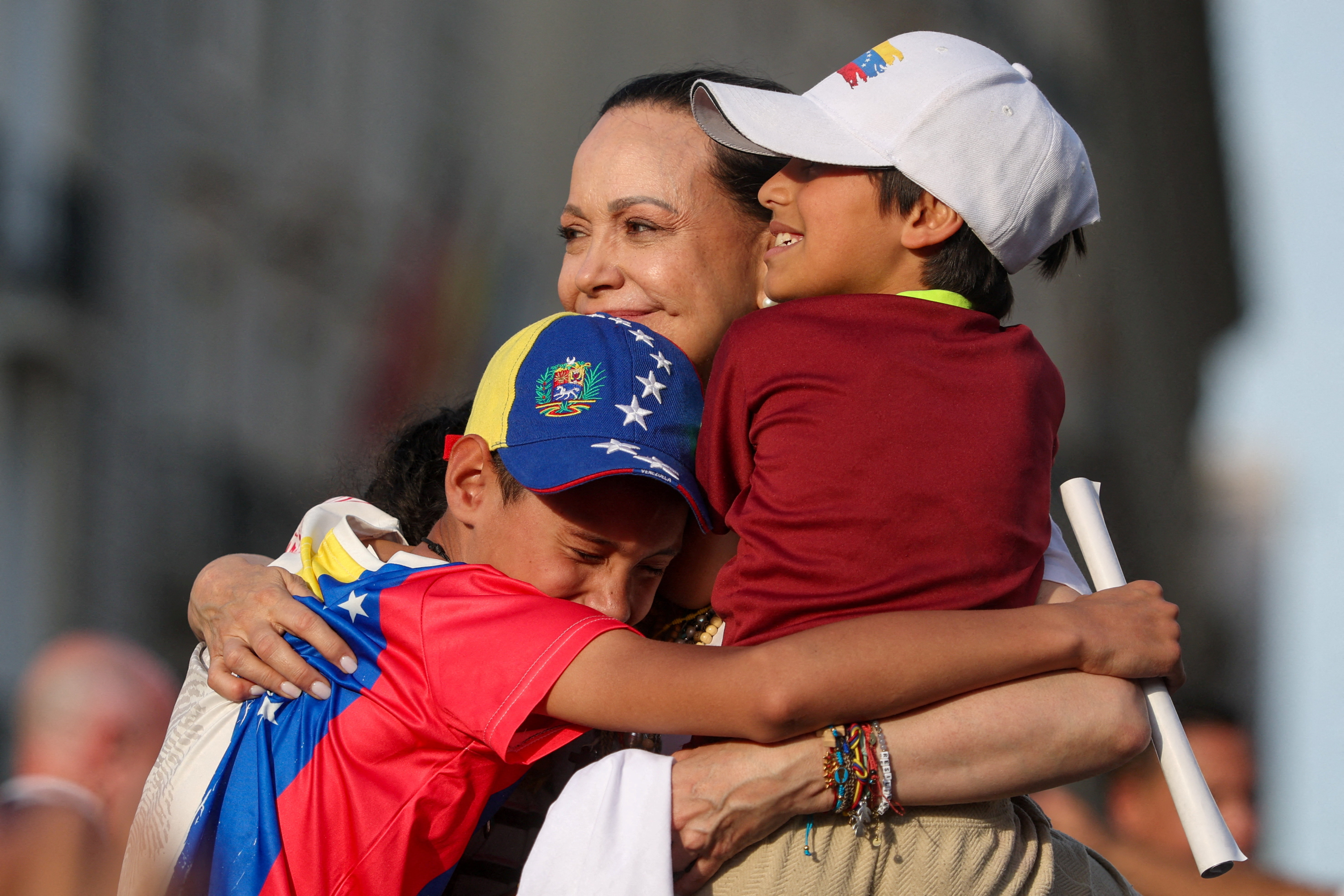Venezuelan opposition leader Maria Corina Machado embraces children as she attends a rally in Madrid, Spain