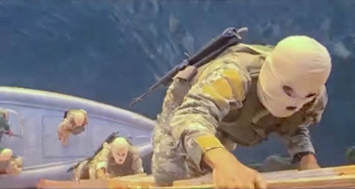 Armed men wearing head coverings climb on board a ship.