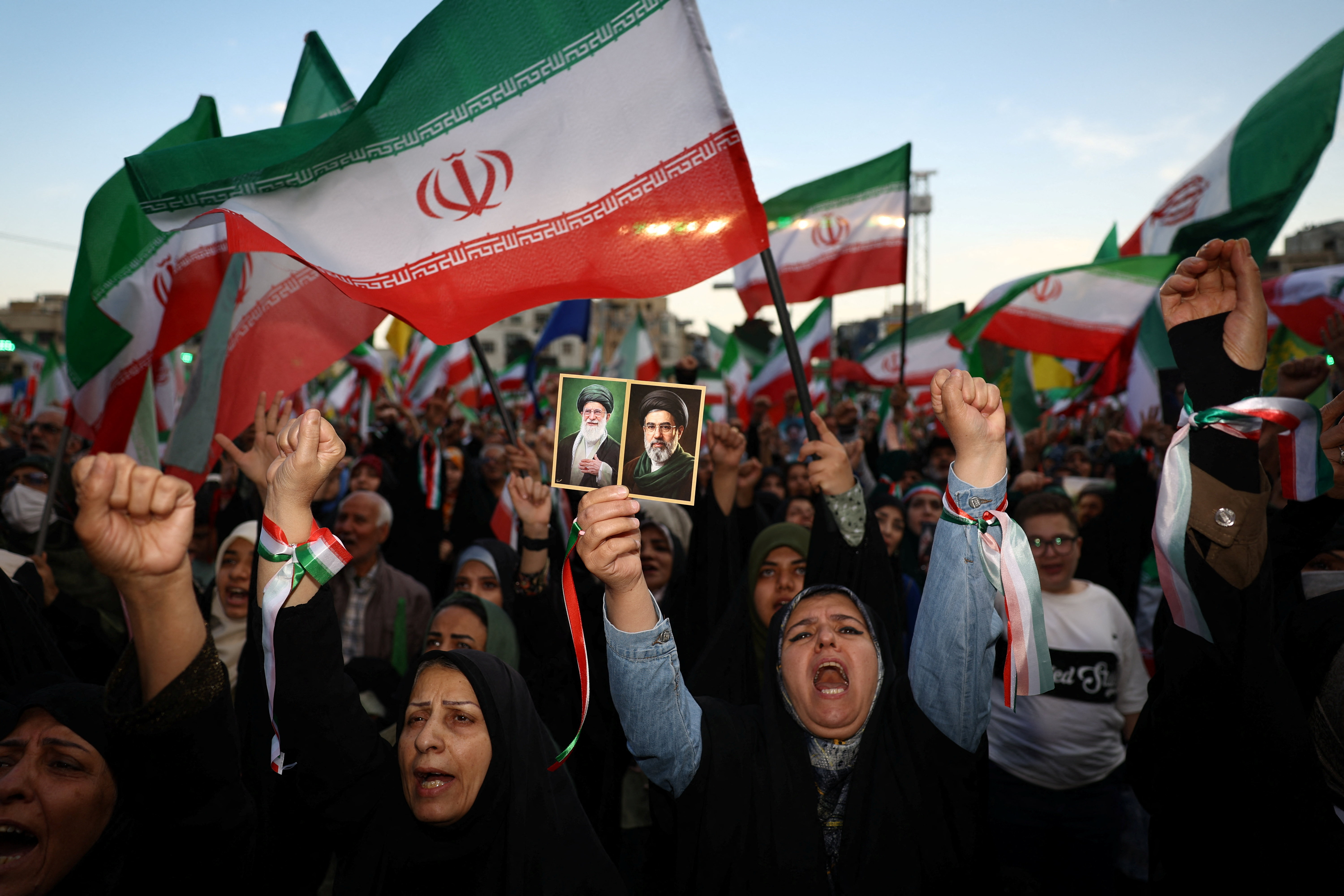 People hold Iranian flags and chant during a rally.