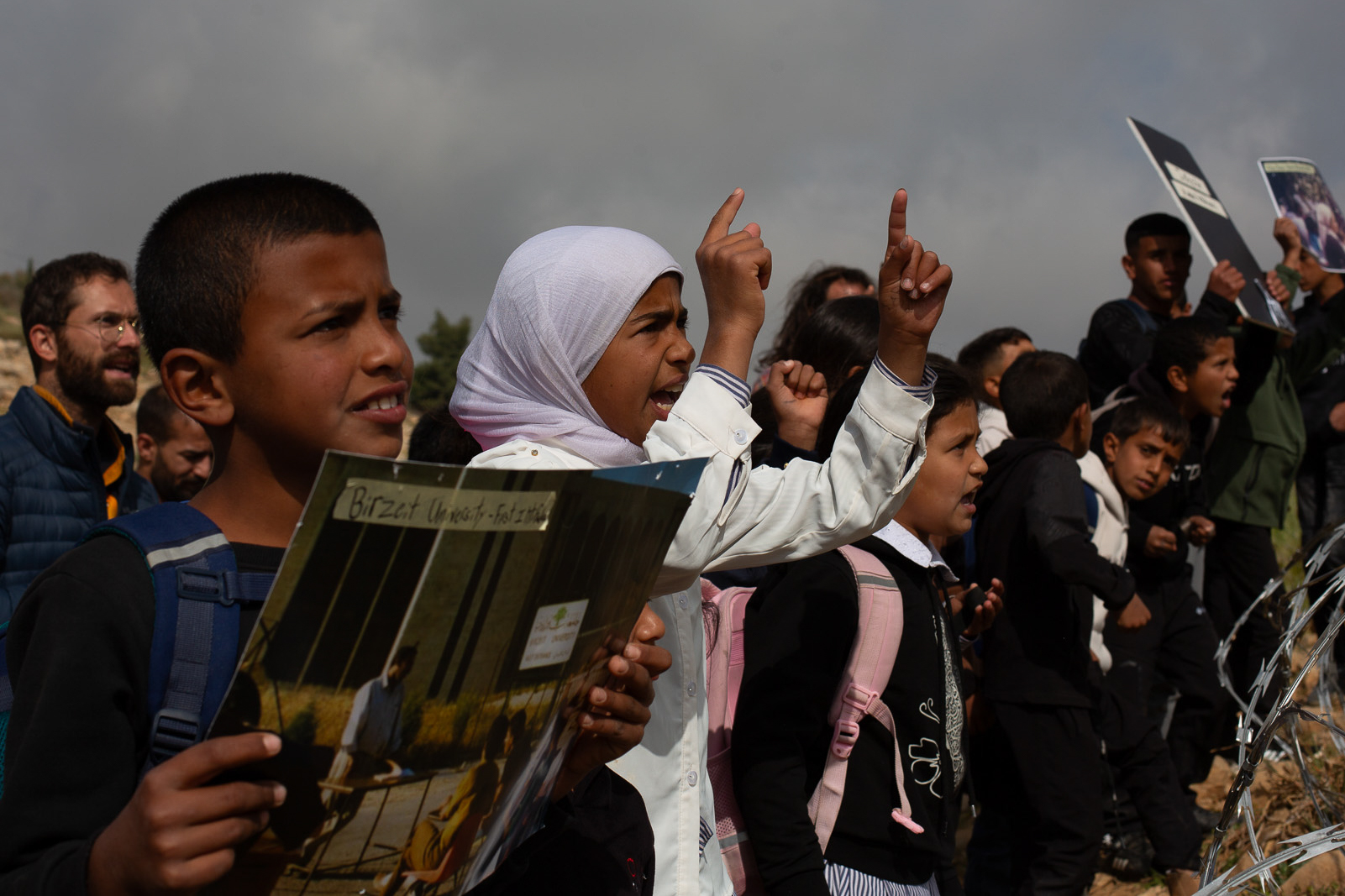 Kids at fence at Umm al-Khair telling soldiers to open road [Steven Davidson/Al Jazeera]