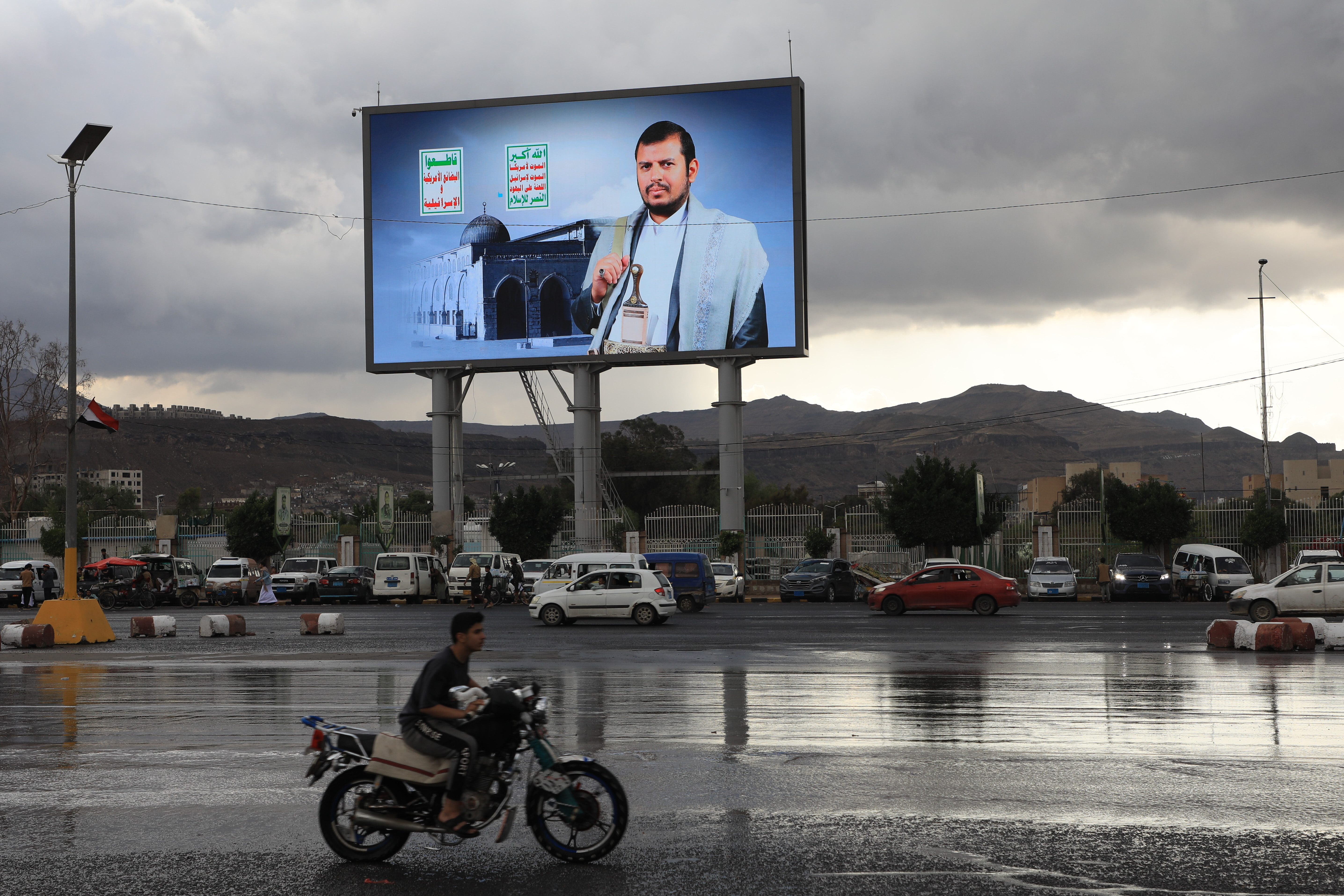 Vehicles pass under a banner showing Houthi leader Abdul Malik al-Houthi, in Sanaa, Yemen, Tuesday, March 31, 2026. (AP Photo/Osamah Abdulrahman)