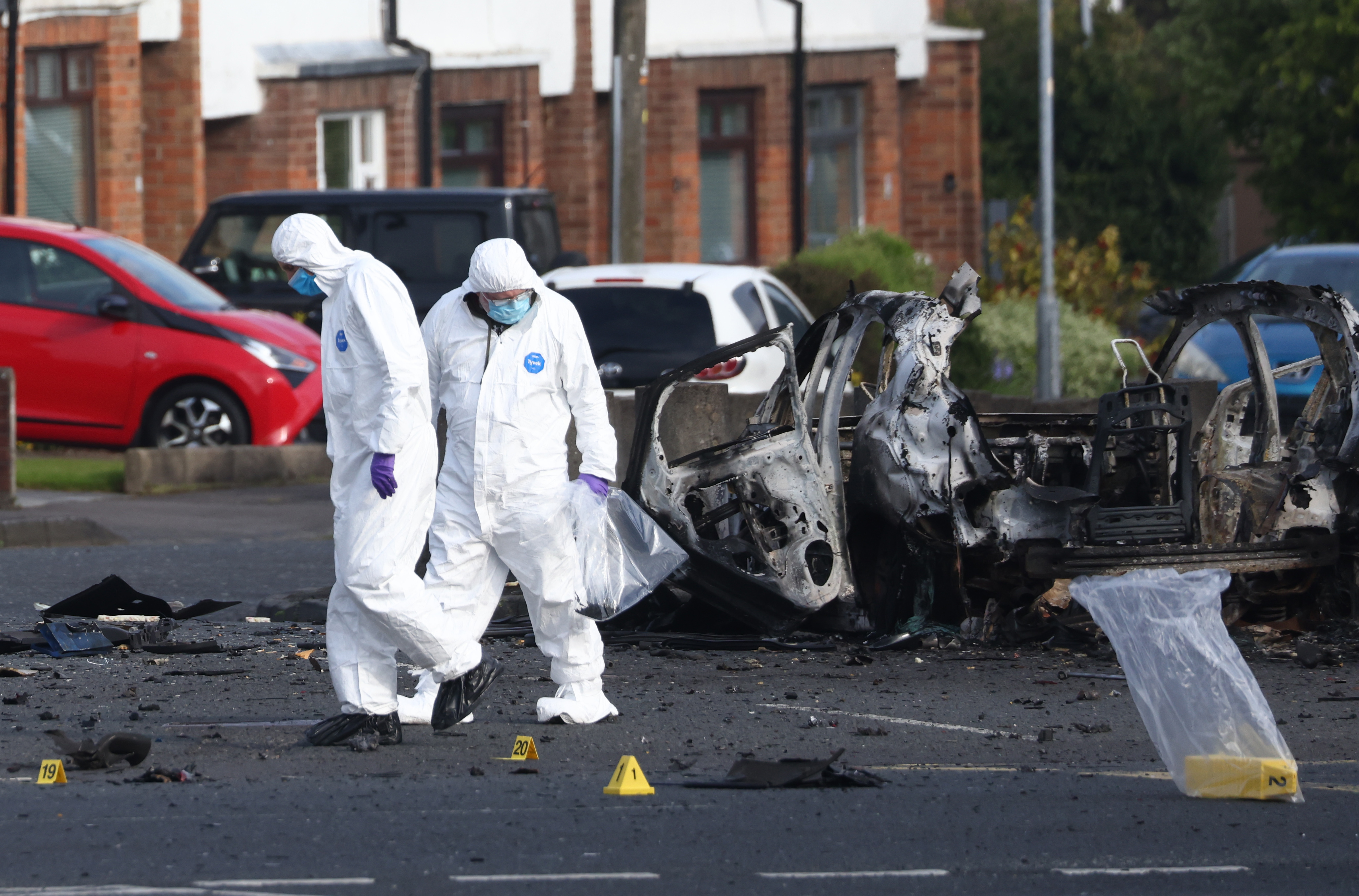Forensic investigators inspect the site of a car bomb that exploded outside Dunmurry police station in South Belfast, Sunday, April 26, 2026. (AP Photo/Peter Morrison)