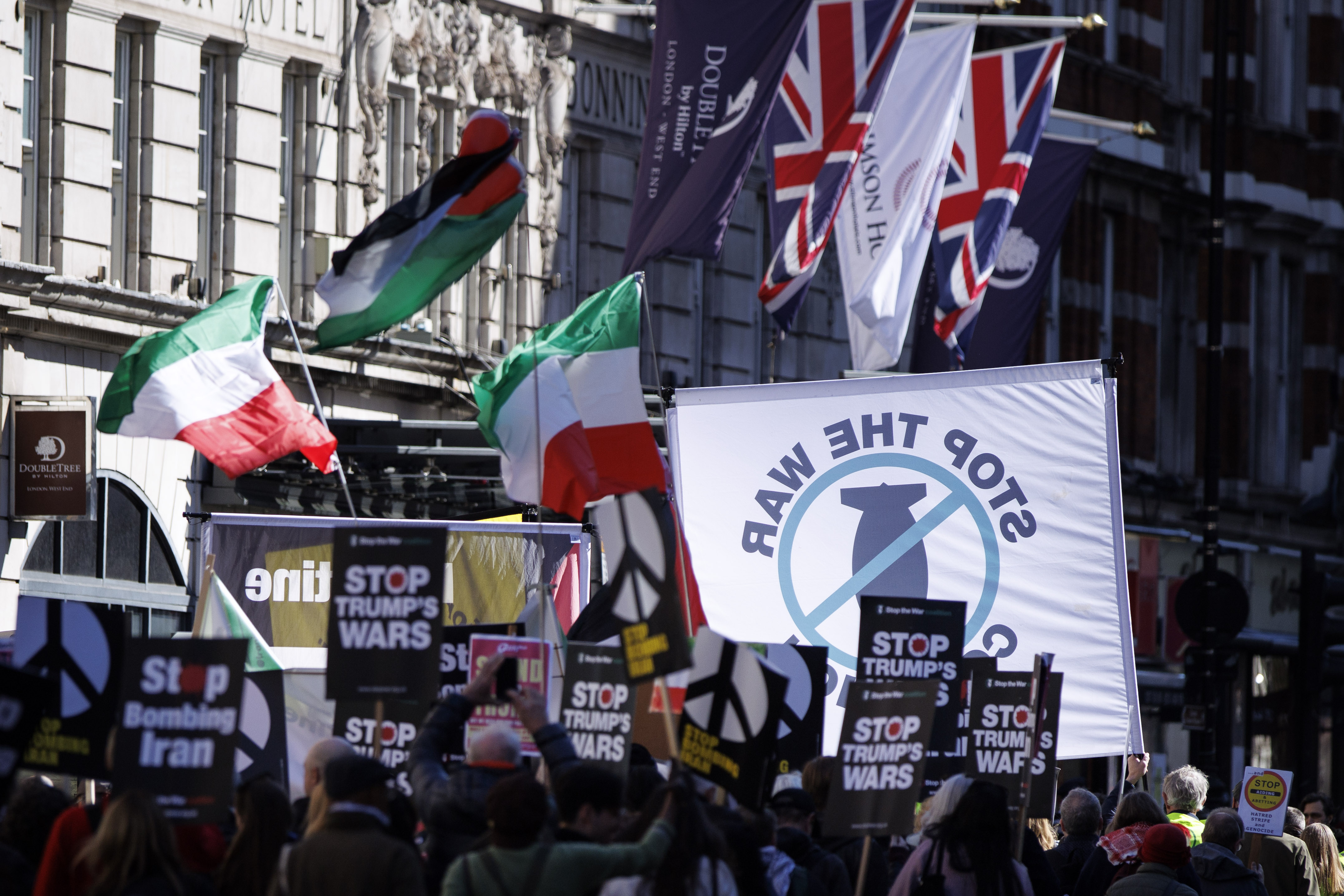 epa12838797 People display placards and wave flags as they attend the 'Stop Bombing Iran' march to Whitehall, in London, Britain, 21 March 2026. The march is part of a national day of action organized by the Stop the War Coalition to protest US and Israeli involvement in the escalating conflict with Iran and the Middle East. EPA/TOLGA AKMEN