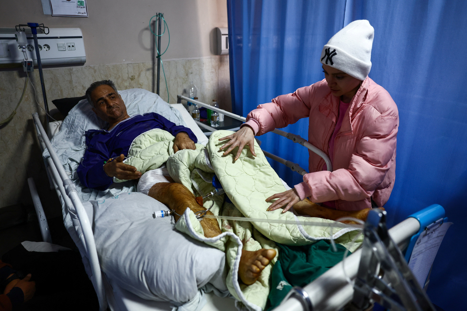 A person assists an Iranian man, injured in a strike on the B1 bridge, who is being treated at Imam Ali Hospital amid the US-Israeli conflict with Iran, in Karaj, Iran on April 3, 2026. [Majid Asgaripour/WANA via Reuters]