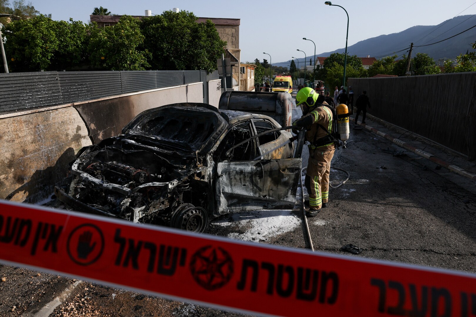 A firefighter uses an hose at an impact site, in Kiryat Shmona, Israel on April 16, 2026. [Florion Goga/Reuters]