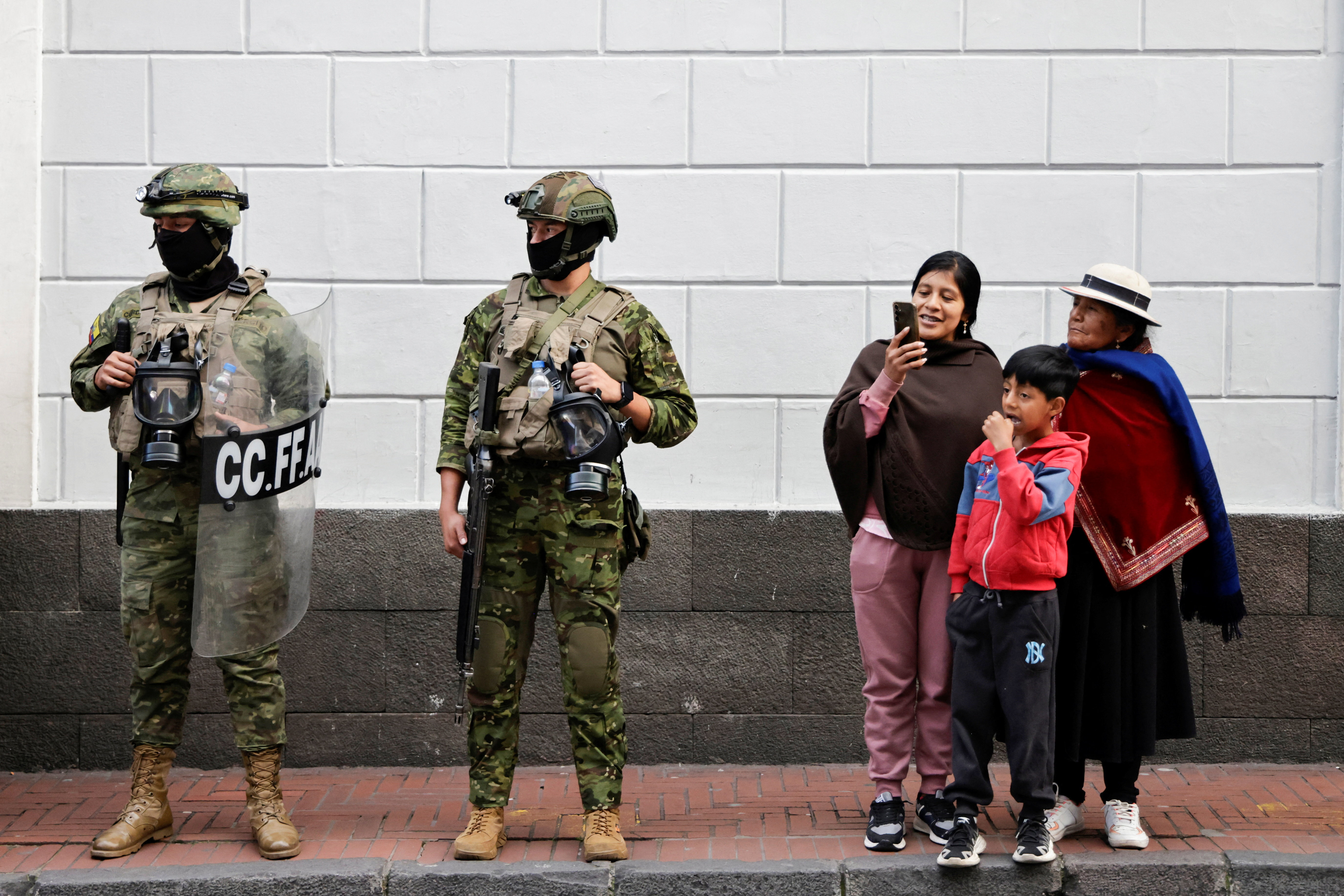 Soldiers and an Indigenous family look on during a march against Ecuador's President Daniel Noboa's government as protesters demand labour rights and social security, as well as access to healthcare and education, in Quito, Ecuador, March 13, 2026. REUTERS/Karen Toro
