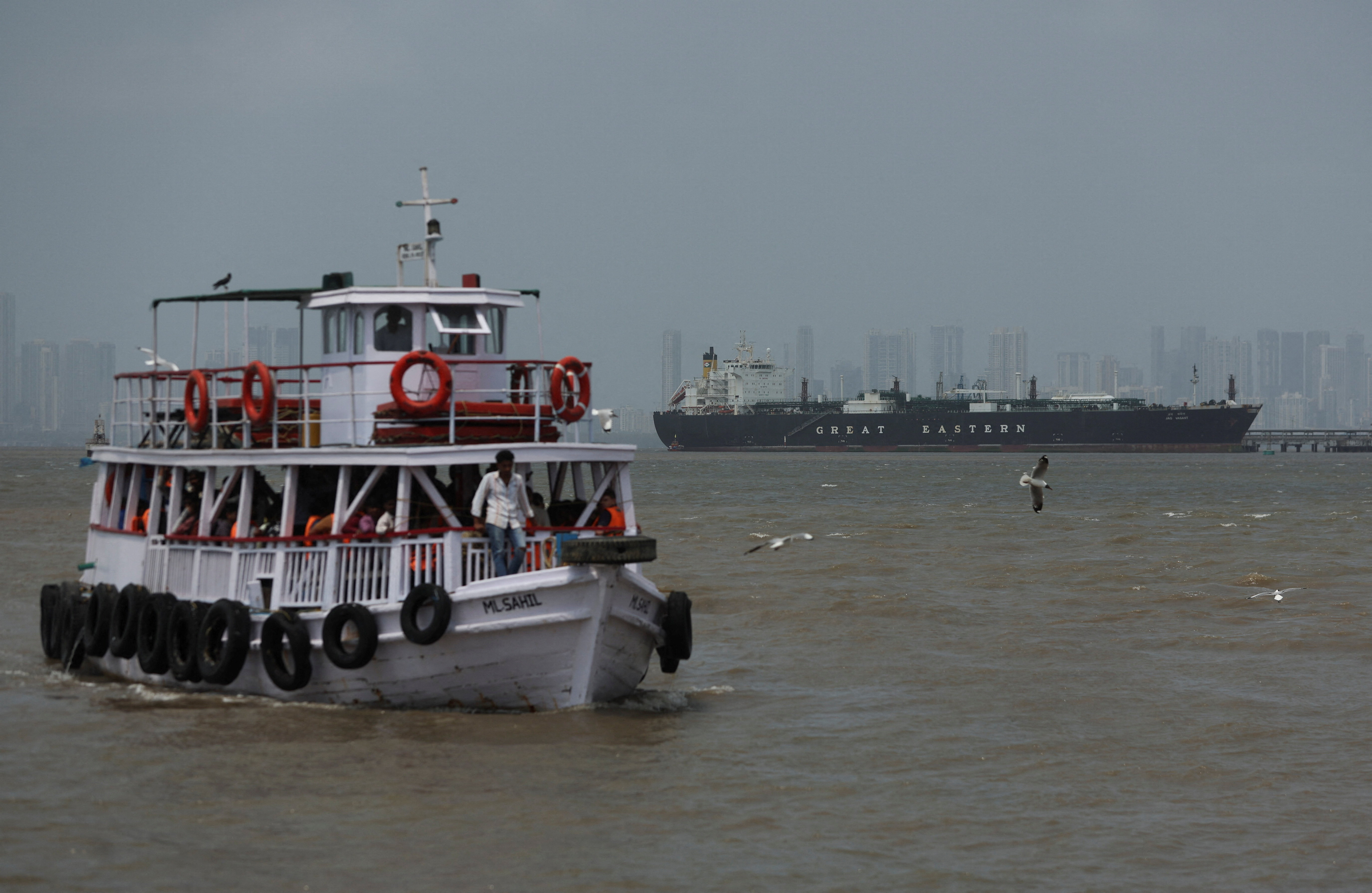 A ferry moves past the Jag Vasant vessel transferring LPG at a port after transiting the Strait of Hormuz amid supply disruptions linked to the U.S-Israeli conflict with Iran, in Mumbai, India, April 1, 2026. REUTERS/Francis Mascarenhas