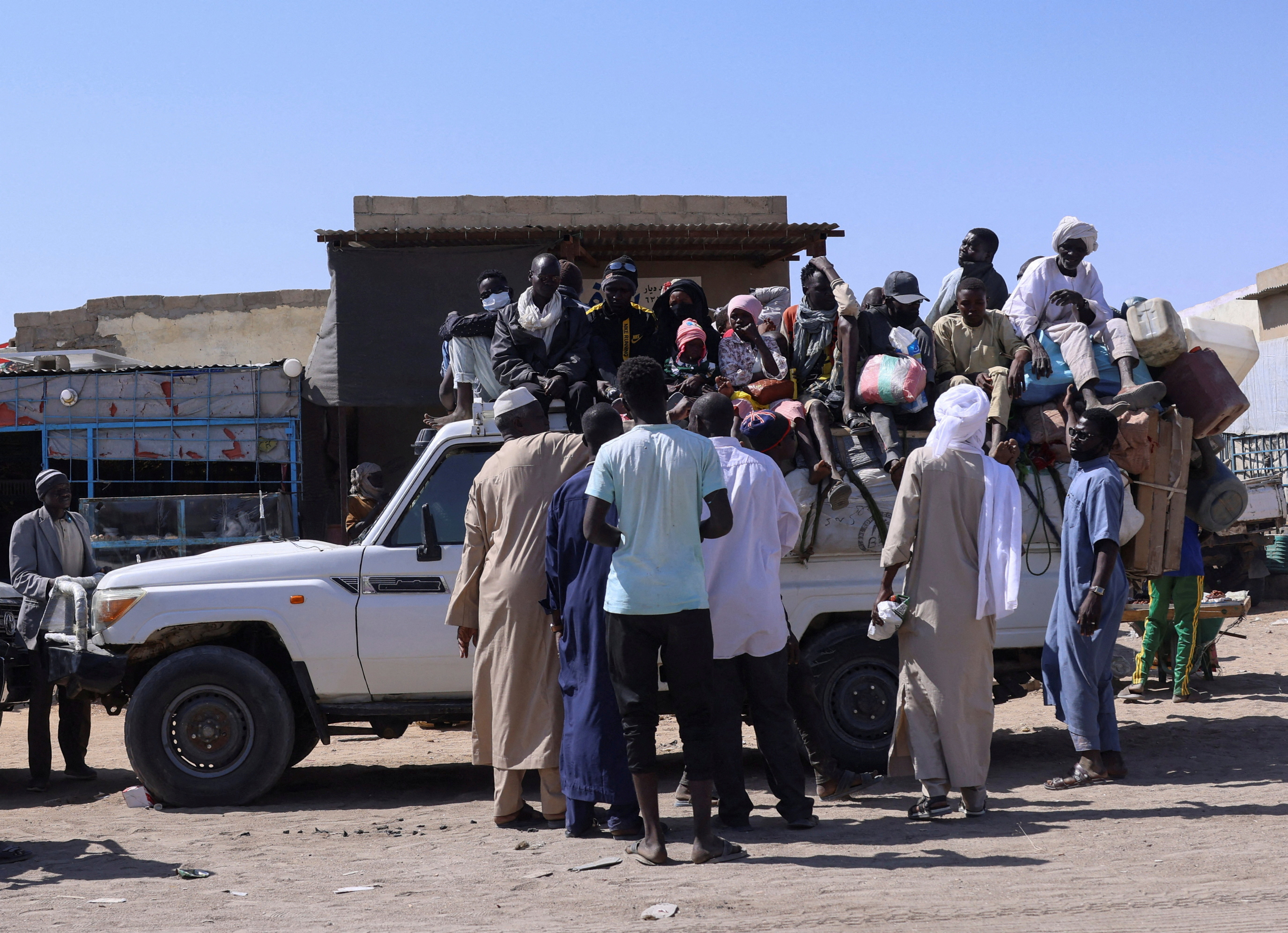 FILE PHOTO: People sit on a pickup truck as they prepare to travel about 250 km south to Adre, on the Chad-Sudan border, at a transport station in Tine, eastern Chad, November 25, 2025. REUTERS/Amr Abdallah Dalsh/File Photo