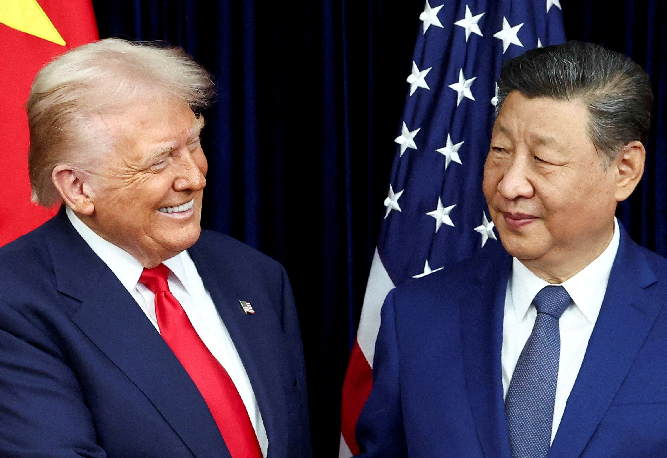 U.S. President Donald Trump and Chinese President Xi Jinping react as they hold a bilateral meeting at Gimhae International Airport