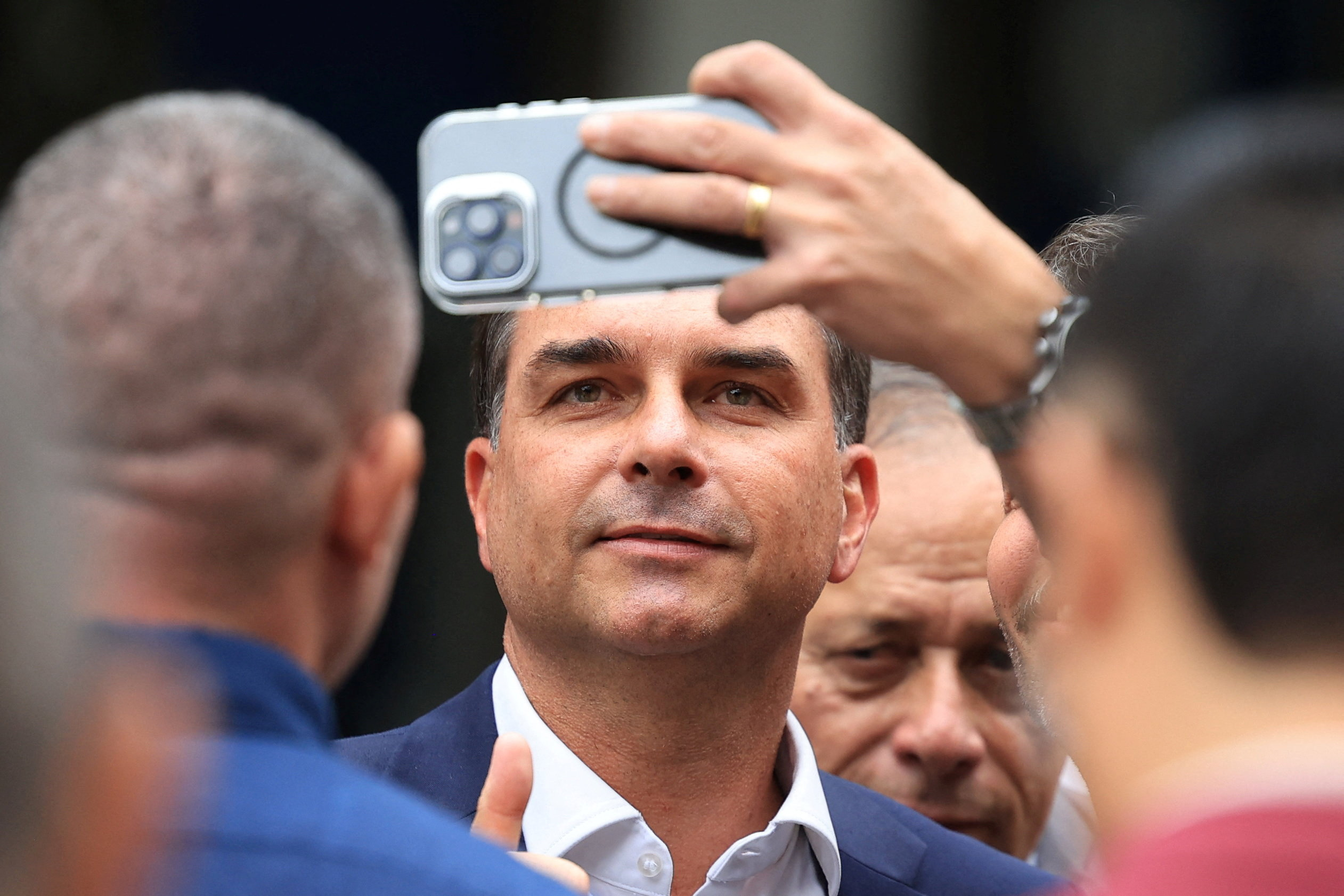 Senator Flavio Bolsonaro poses for a selfie as he attends a ceremony at the Military Police headquarters, following the scandal over messages tied to his request for funding for a biopic about former Brazilian President Jair Bolsonaro, from disgraced banker Daniel Vorcaro, who was arrested in March on suspicion of leading a multibillion-dollar fraud scheme, in Rio de Janeiro, Brazil, May 15, 2026. REUTERS/Pilar Olivares