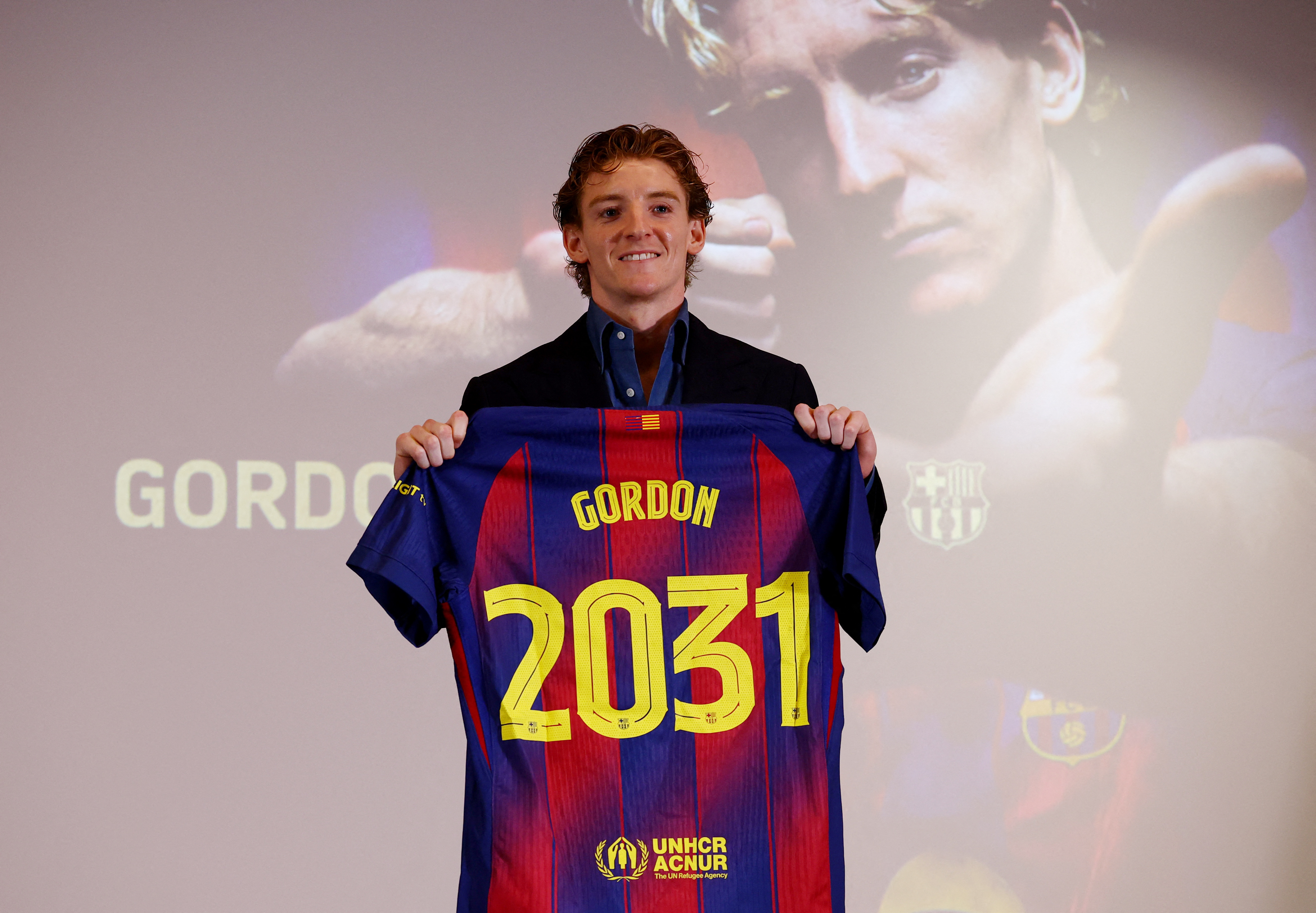 Anthony Gordon poses as he holds a shirt.