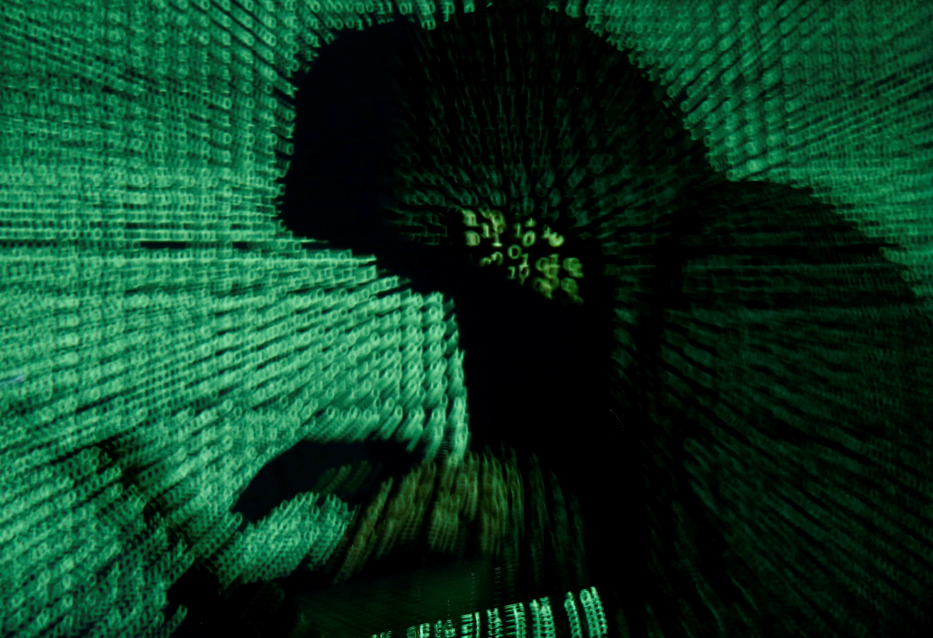 FILE PHOTO: A man holds a laptop computer as cyber code is projected on him in this illustration picture created on May 13, 2017. REUTERS/Kacper Pempel/Illustration/File Photo