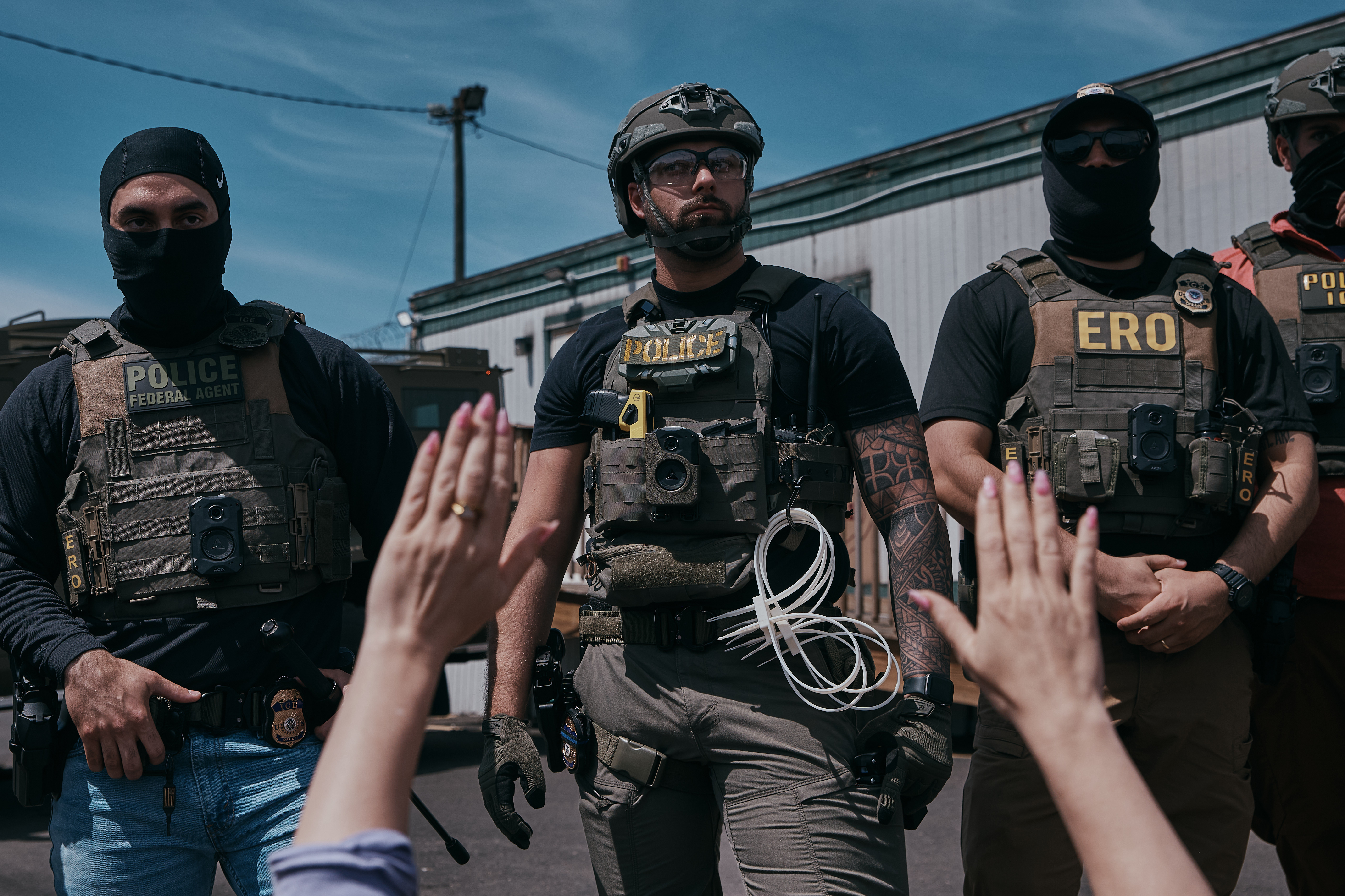 A protester holds her hands up at ICE agents.