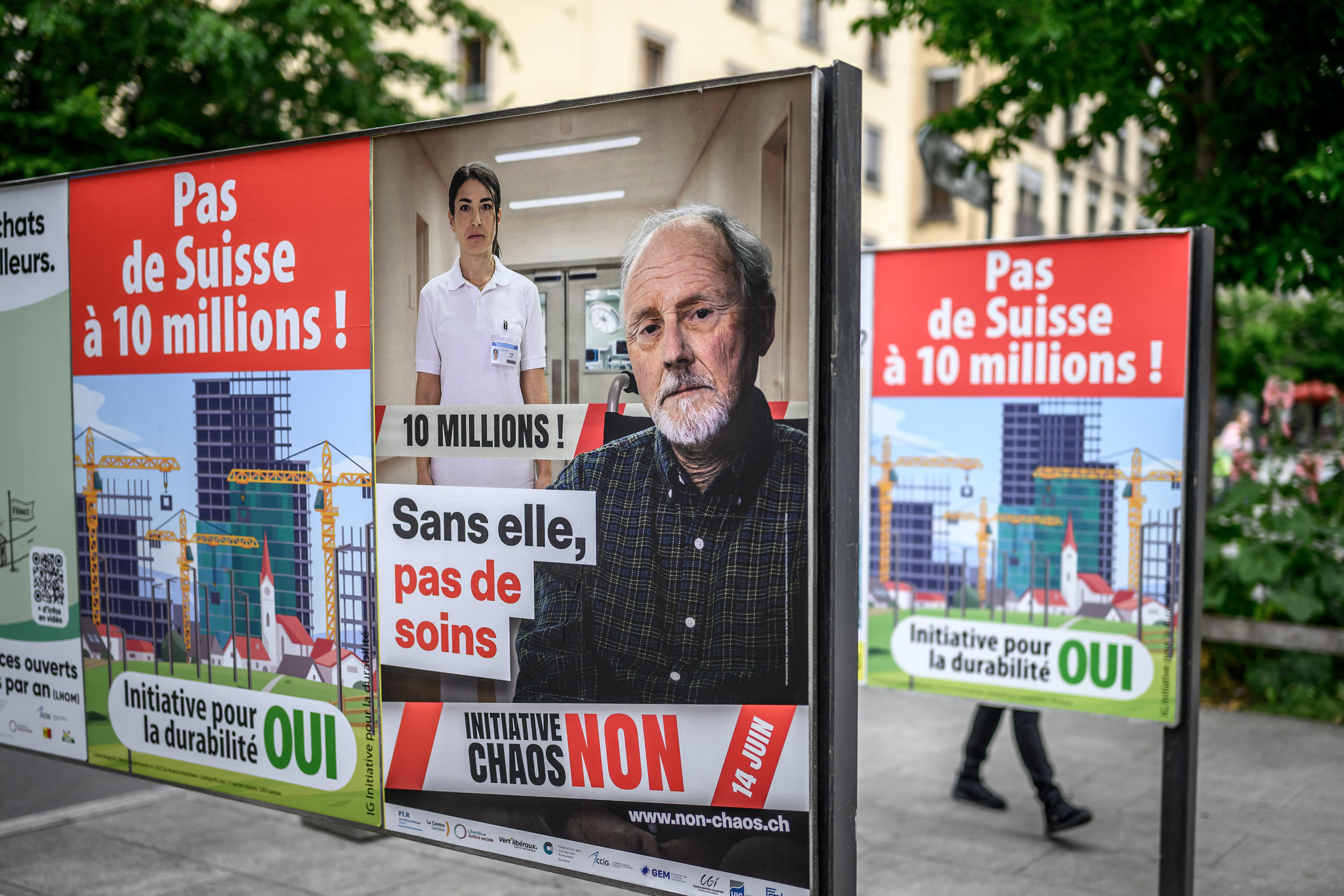 This photograph shows campaign posters for and against a nationwide vote on an anti-immigration initiative, reading (L and R) "No to a Switzerland of 10 million!" and (C) "Without her, there would be no care."