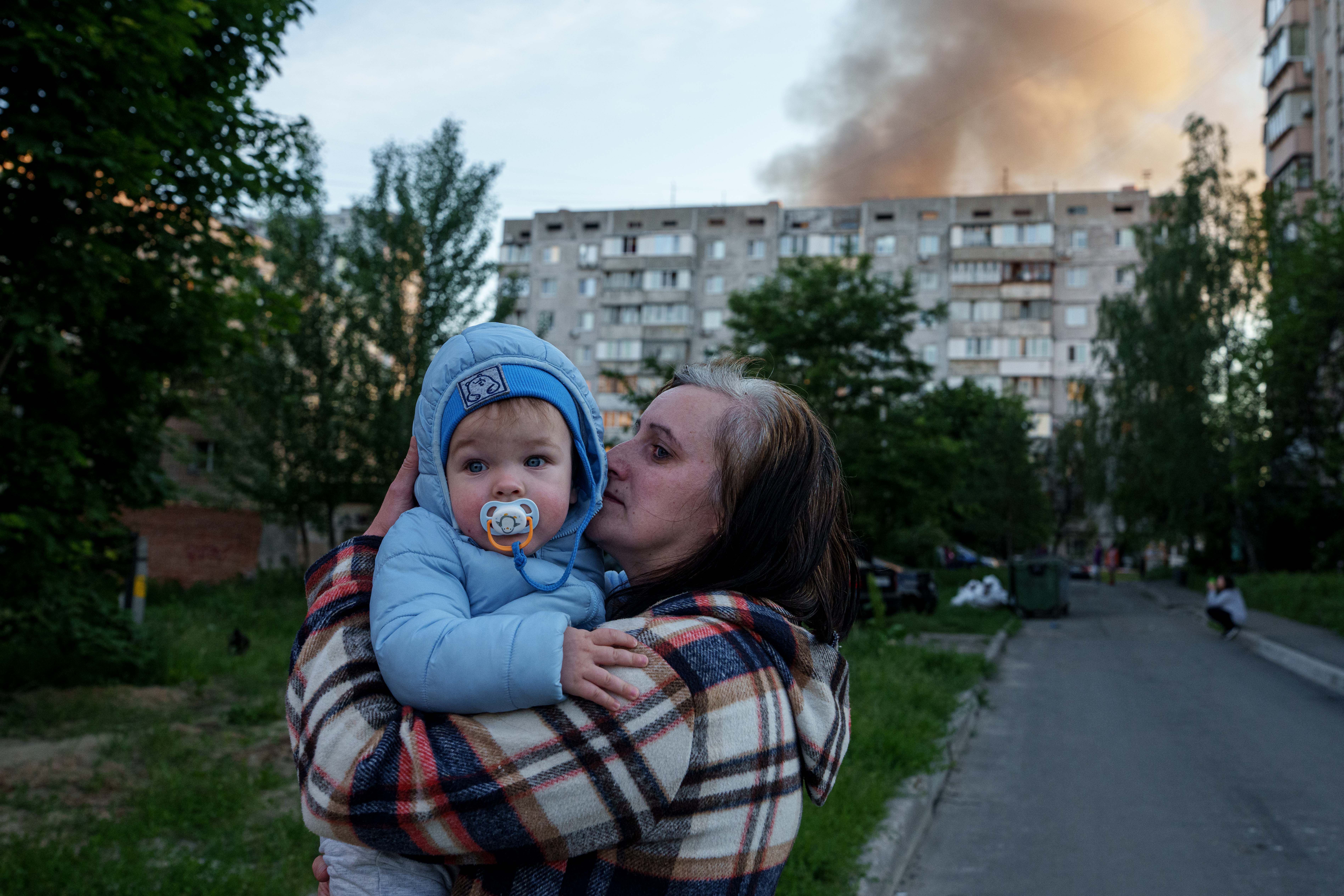 A woman carries a baby near a residential house damaged after a Russian strike in Kyiv, Ukraine, on Tuesday, June 2, 2026. (AP Photo/Evgeniy Maloletka)