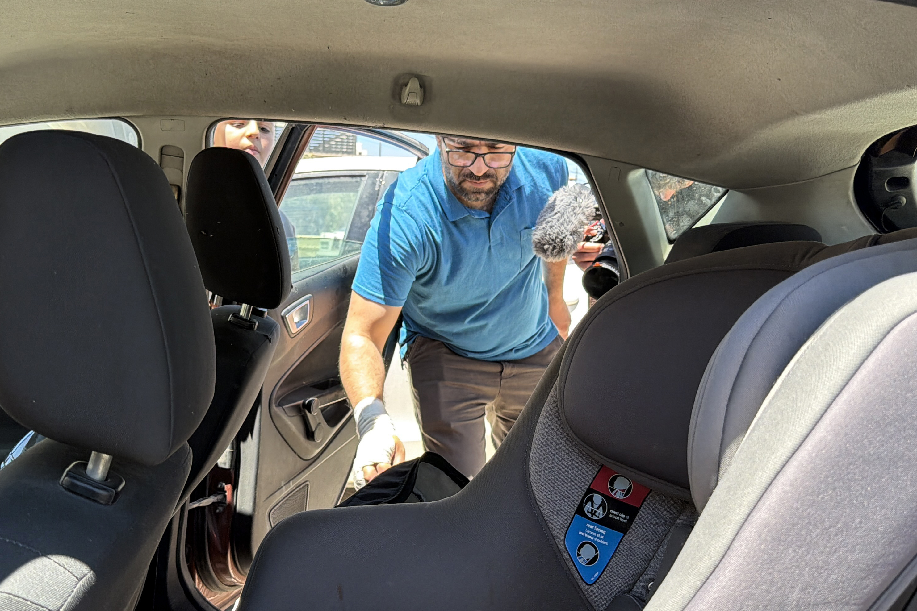 Fahd Abu Haikal inspects the car where his seven-month-old child, Sam, was shot dead
