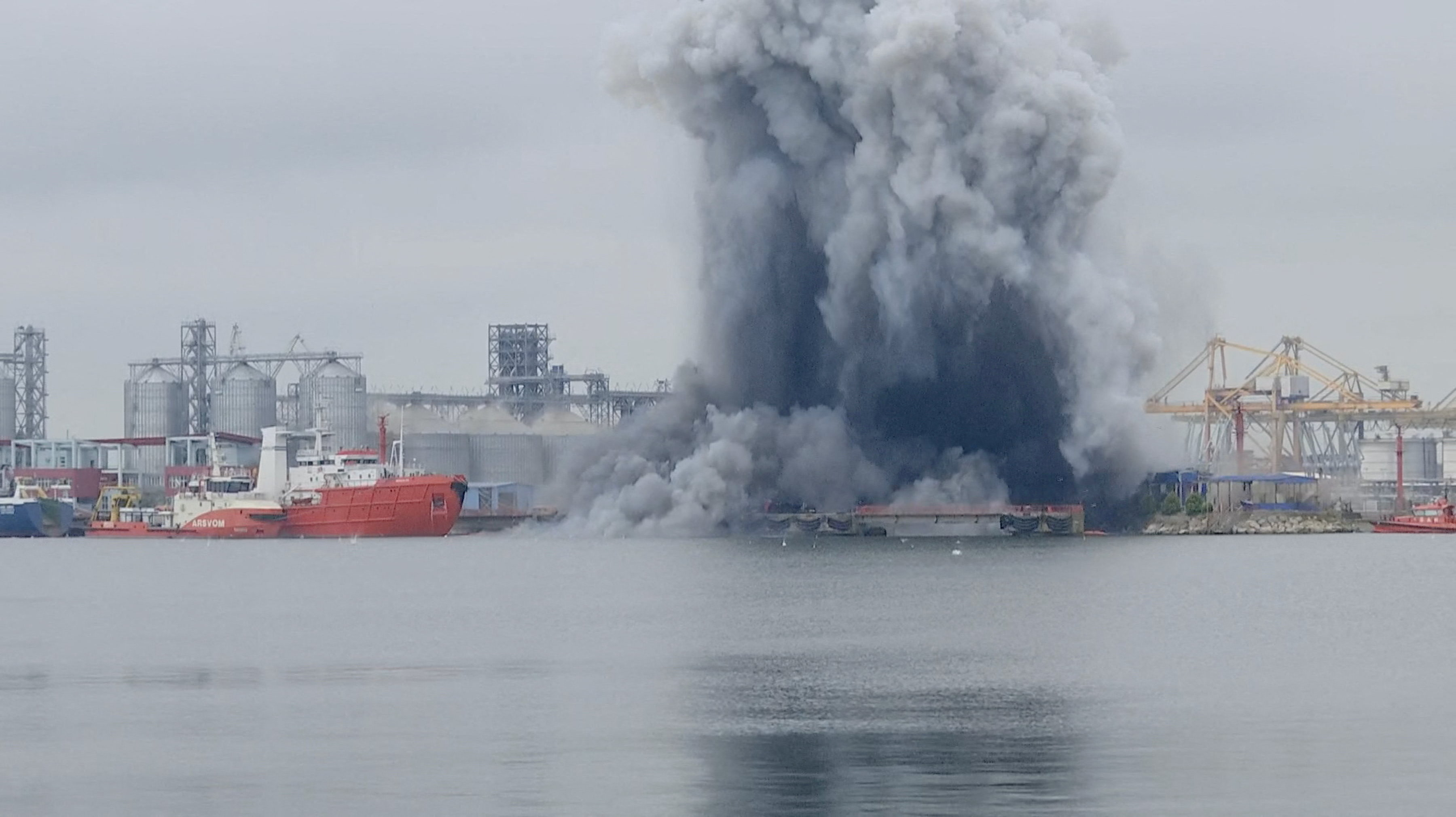 Smoke rises after an explosion by the sea.