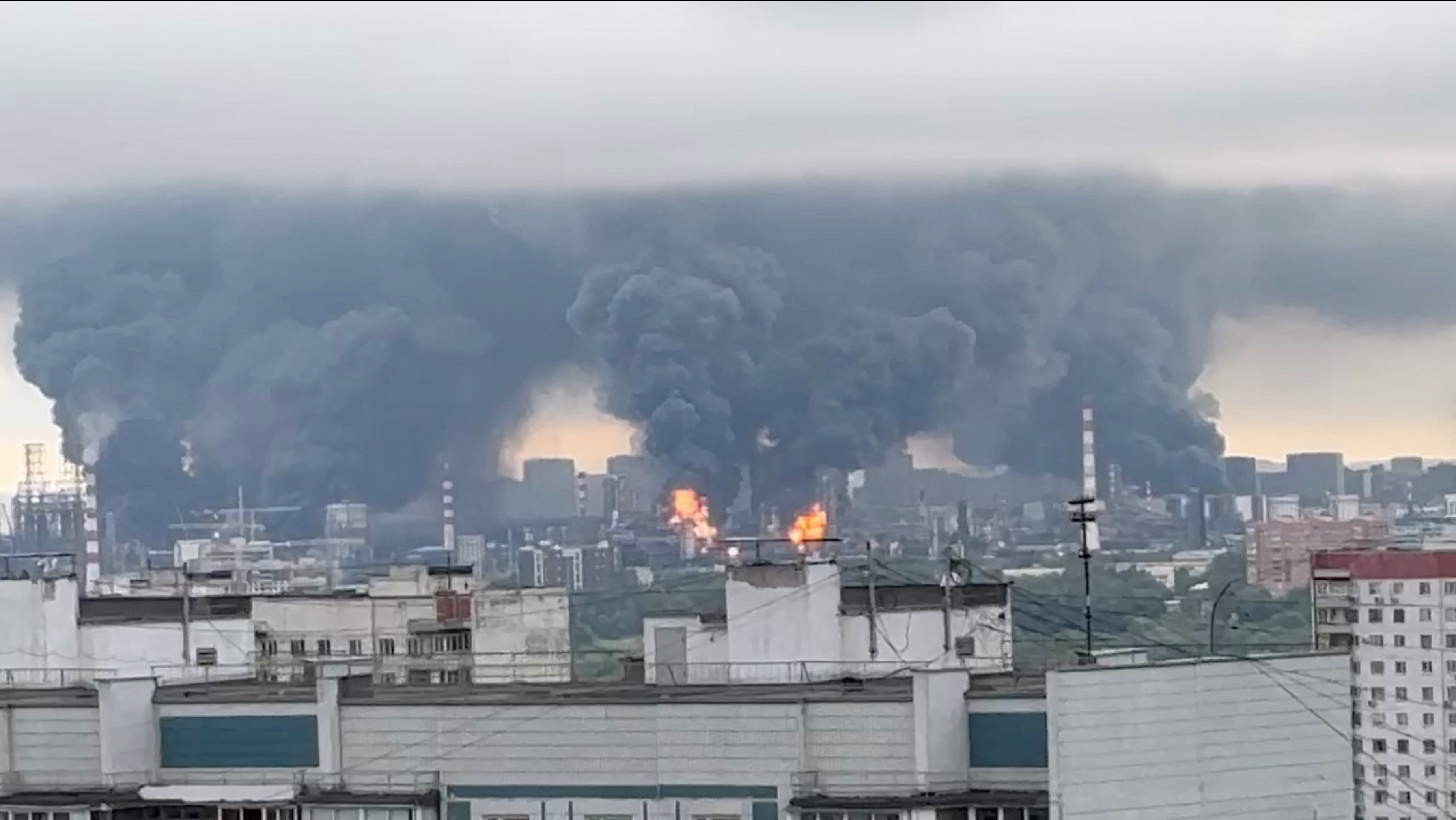 Smoke rises in the distance over a cityscape