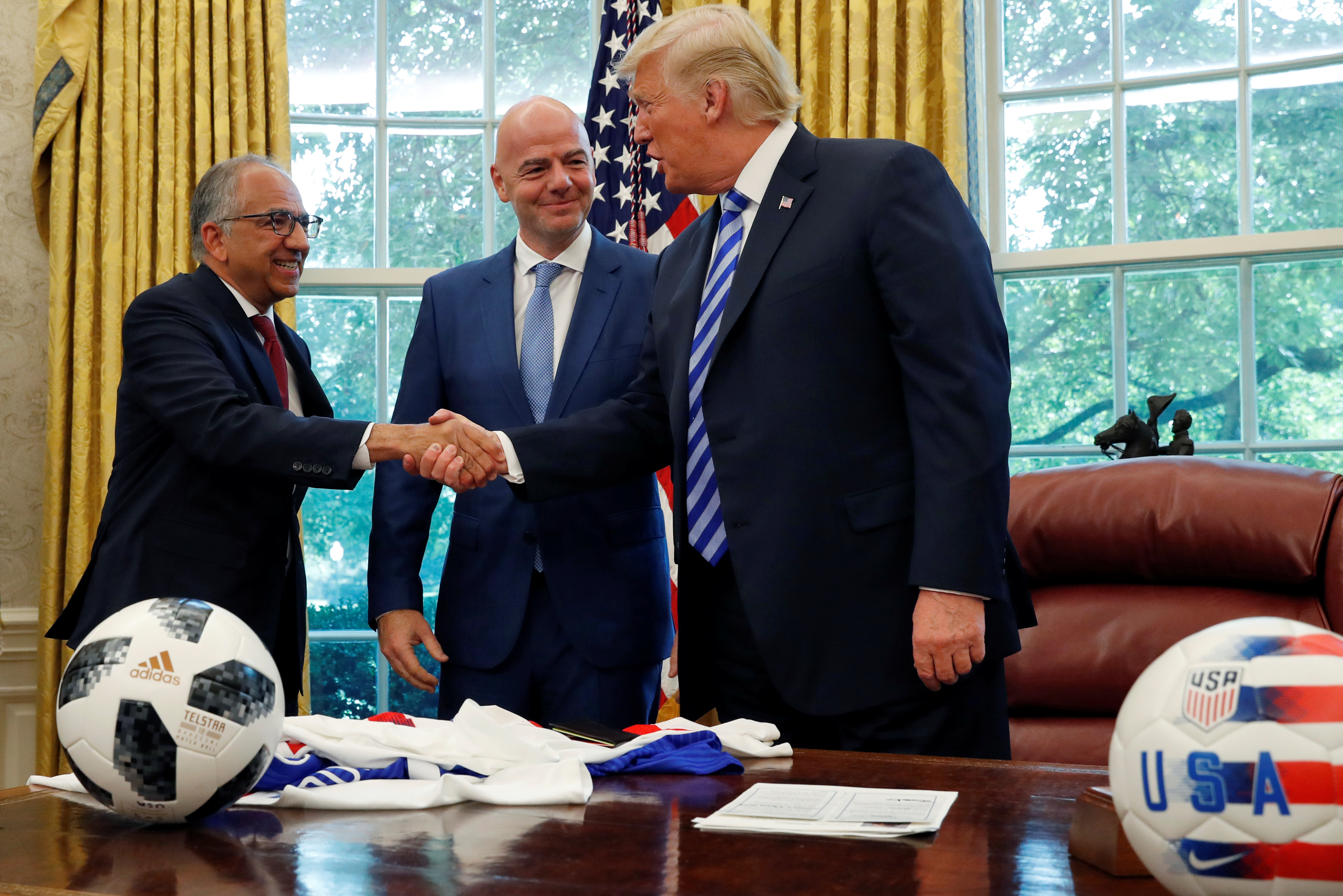 US President Donald Trump shakes hands with Carlos Cordeiro, president of the US Soccer Federation, while meeting with the President of FIFA Gianni Infantino, centre.