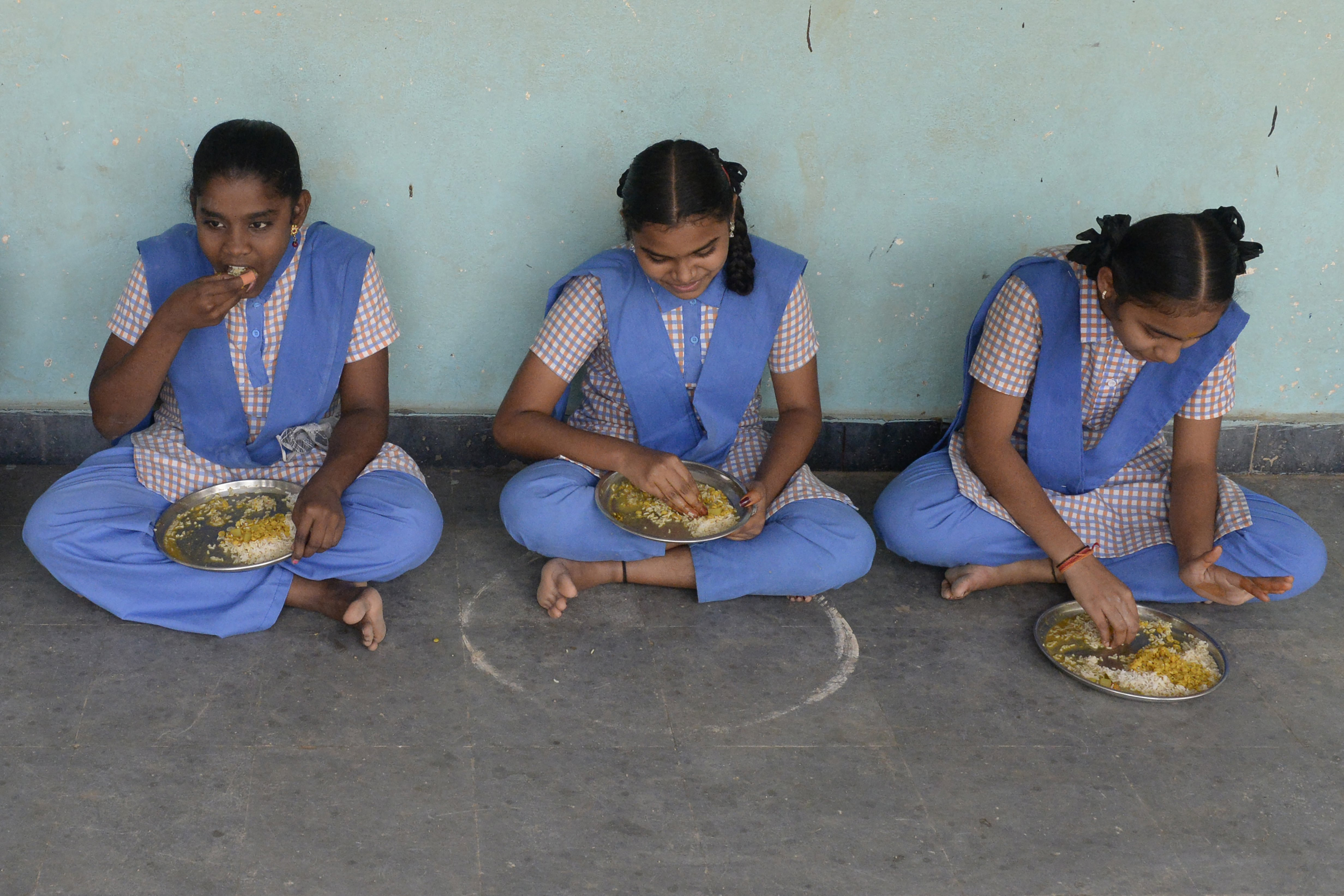 Students eat their mid-day meal during lunch break at a government high school on the outskirts of Hyderabad on November 23, 2021, as schools reopen after months due to the Covid-19 coronavirus pandemic. (Photo by NOAH SEELAM / AFP)