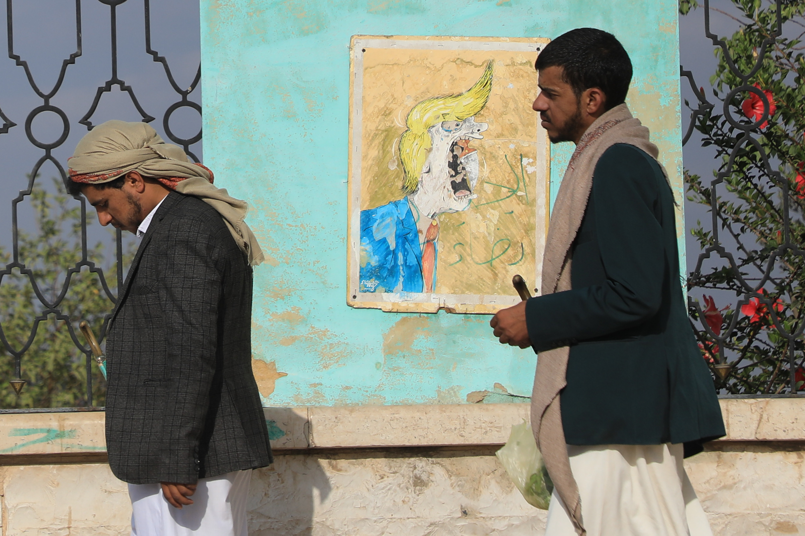 Houthi supporters walk in font of a poster criticizing President Donald Trump in Sanaa, Yemen, Monday, July 13, 2026. (AP Photo/Osamah Abdulrahman)