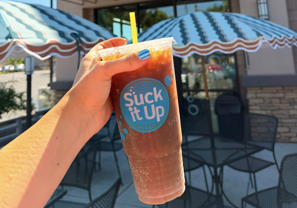 A customer enjoys a dirty soda outside the Suck It Up dirty soda shop in Bakersfield, California [Michelle Bruton/Al Jazeera]