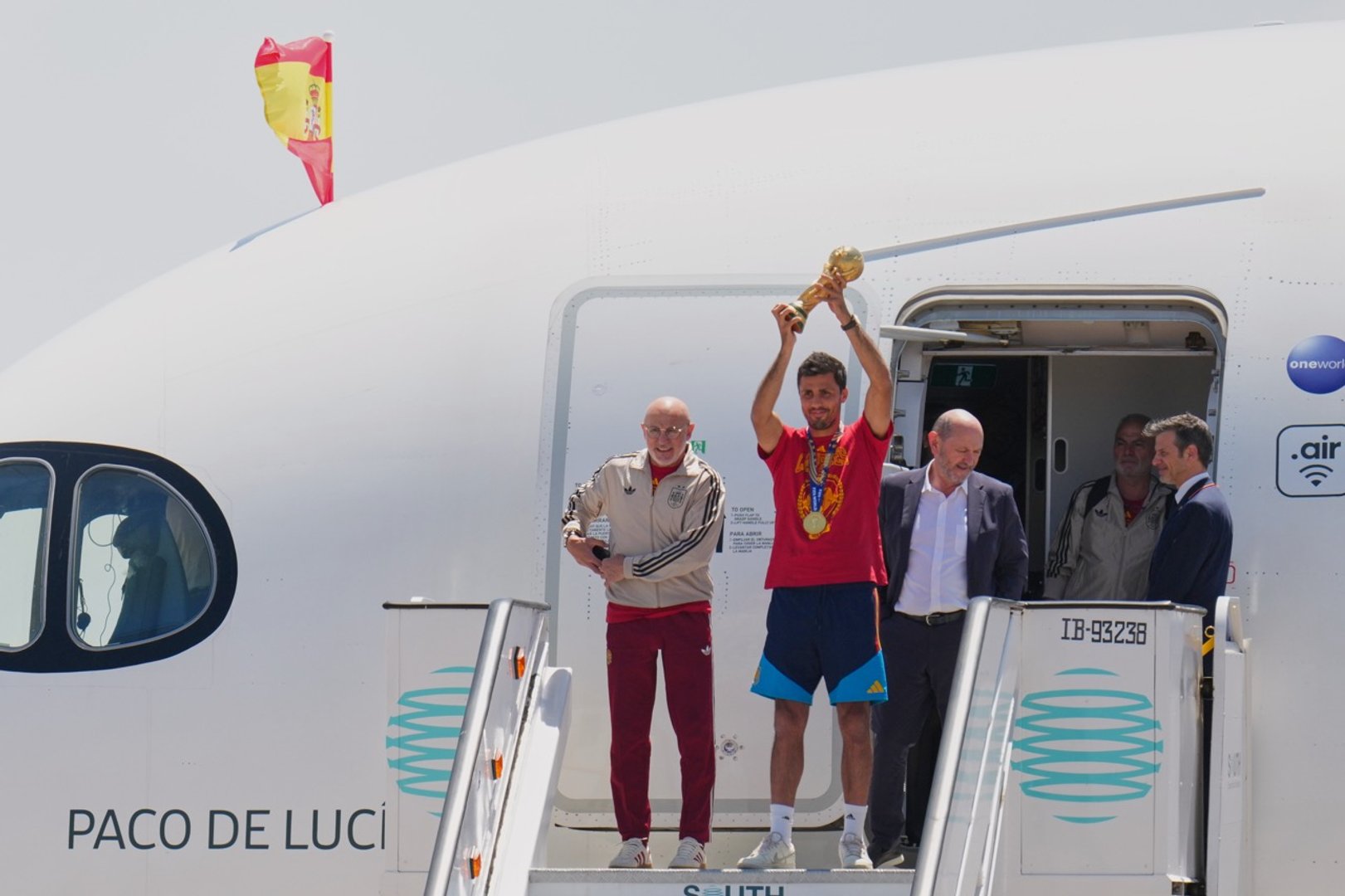 Spain's Rodrigo Hernandez lifts the World Cup trophy alongside Spain head coach Luis de la Fuente, left, and Royal Spanish Football Federation President Rafael Louzan as they arrive at Madrid airport on Monday, July 20, 2026, after Spain defeated Argentina in the World Cup final. [AP Photo/Manu Fernandez]
