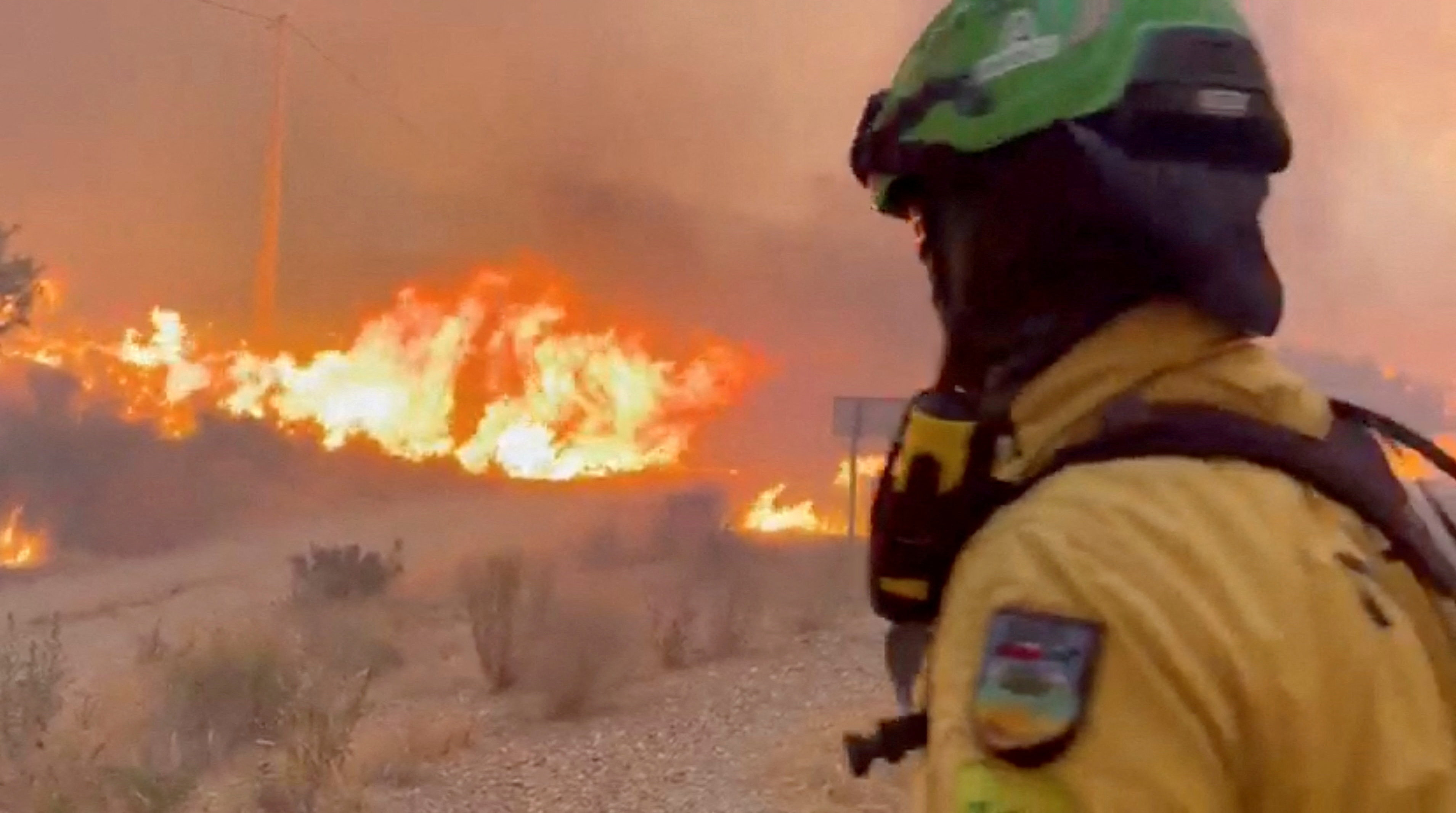 An emergency worker looks on during a wildfire.