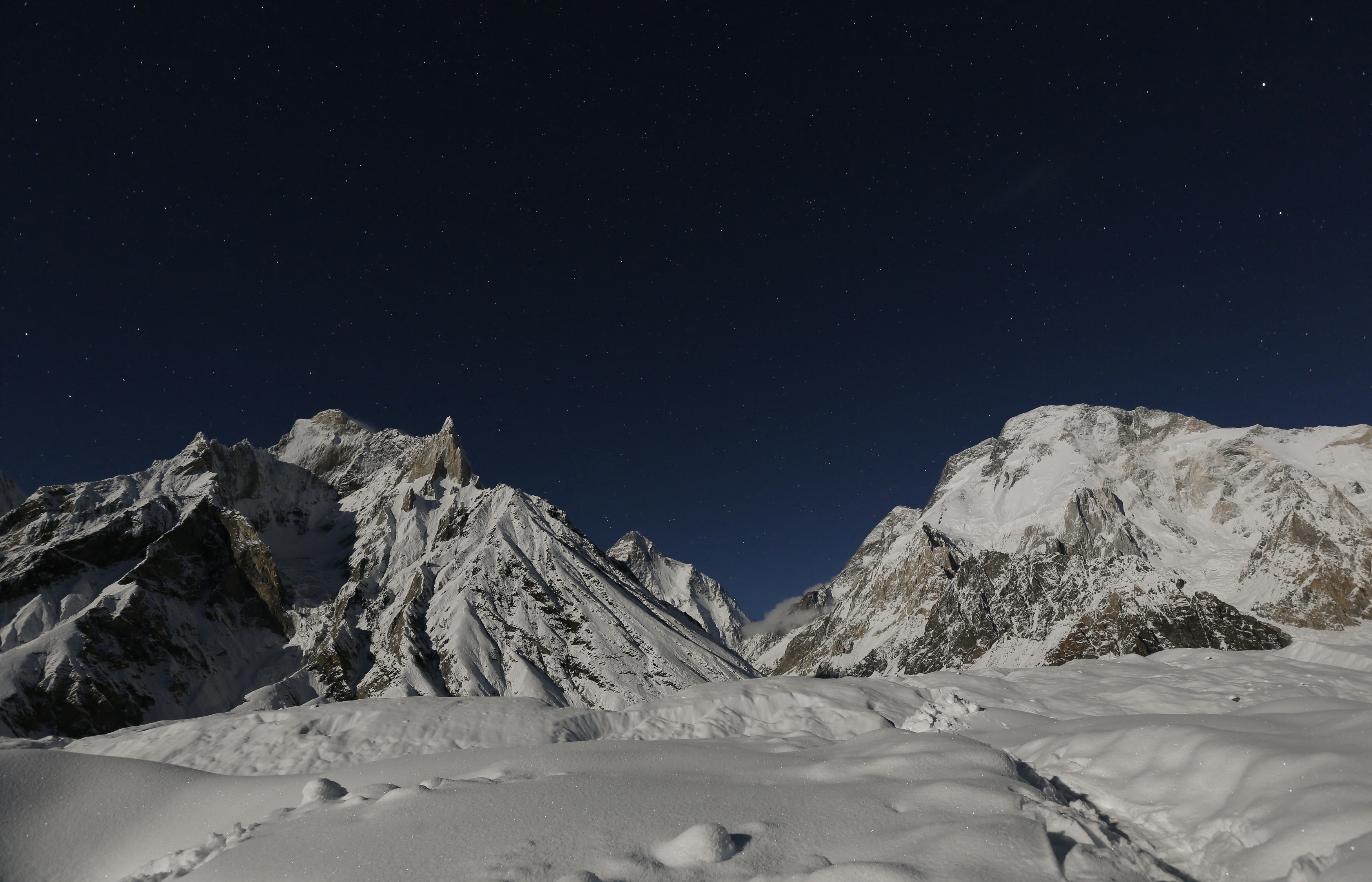 The world's second largest mountain, the 8,611 meter high K2 (seen in the distance), and the 8,051 meter high Broad Peak (R), are illuminated by the moon at Concordia, the confluence of the Baltoro and Godwin-Austen glaciers, in the Karakoram mountain range in Pakistan September 7, 2014. While other parts of Pakistan and northern India were flooded, Concordia in the Karakoram mountain range was covered with a seasonally unusual amount of snow. Geographically, Pakistan is a climbers paradise. It rivals Nepal for the number of peaks over 7,000 meters and is home to the world's second tallest mountain, K2, as well as four of the world's 14 summits higher than 8,000 meters. In more peaceful times, northern Pakistan's unspoilt beauty was a major tourist draw but the potentially lucrative industry has been blighted by years of violence. The number of expeditions has dwindled, wrecking communities dependant on climbing for income and starving Pakistan's suffering economy of much-needed dollars. Picture taken September 7, 2014. REUTERS/Wolfgang Rattay (PAKISTAN - Tags: SOCIETY ENVIRONMENT TRAVEL TPX IMAGES OF THE DAY)