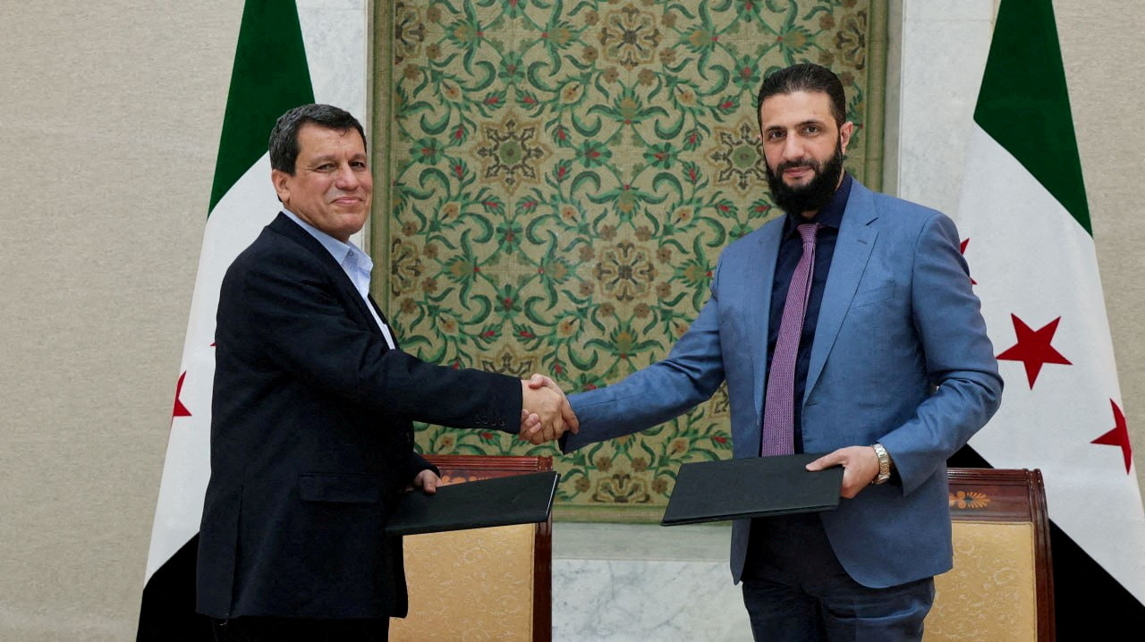 Syrian President Ahmed al-Sharaa and former commander of Syrian Kurdish-led forces Mazloum Abdi shake hands in March 2025 [FILE:Reuters]