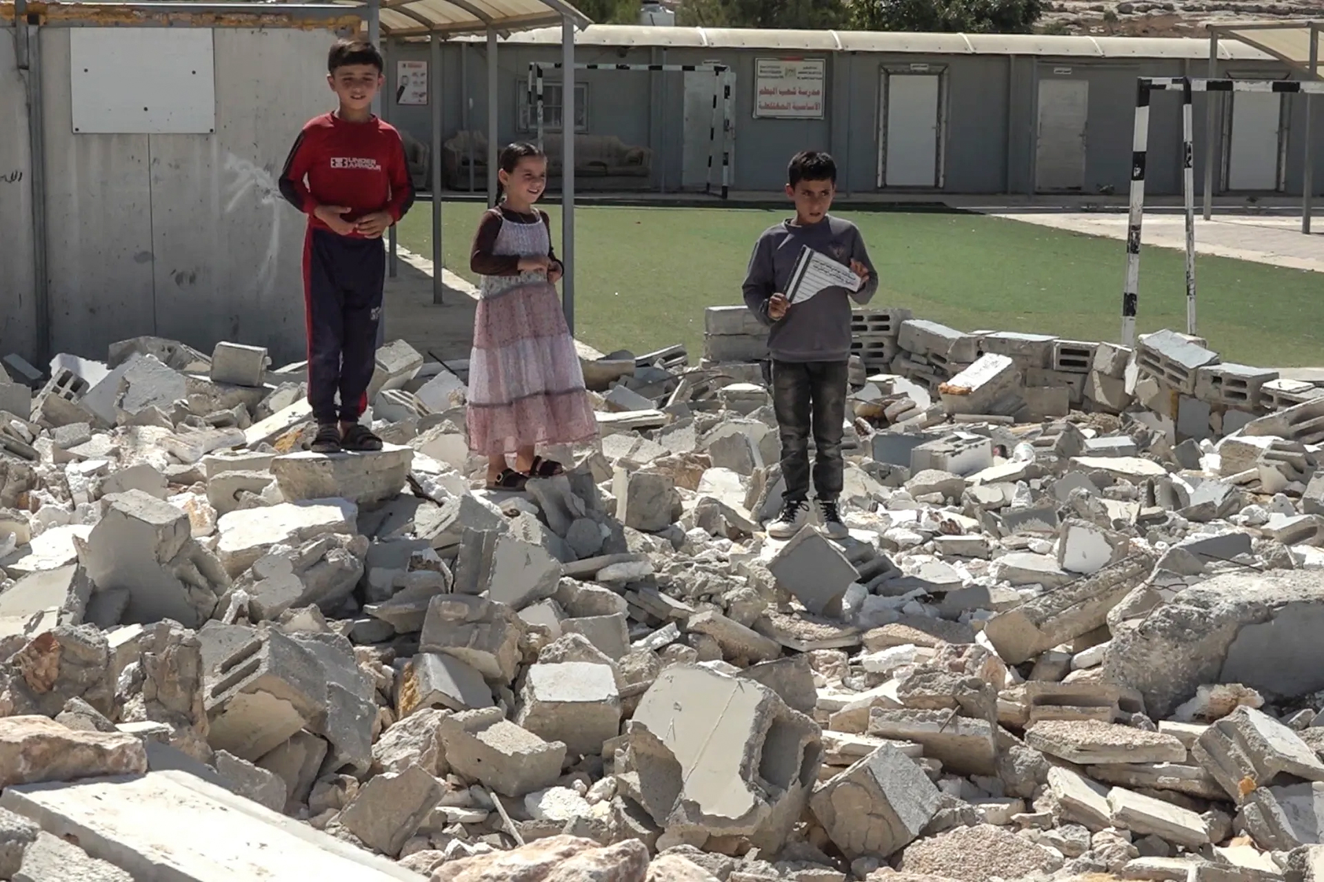 Palestinian children stand on the rubble of the partially demolished Sha'ab al-Butum primary school in Masafer Yatta