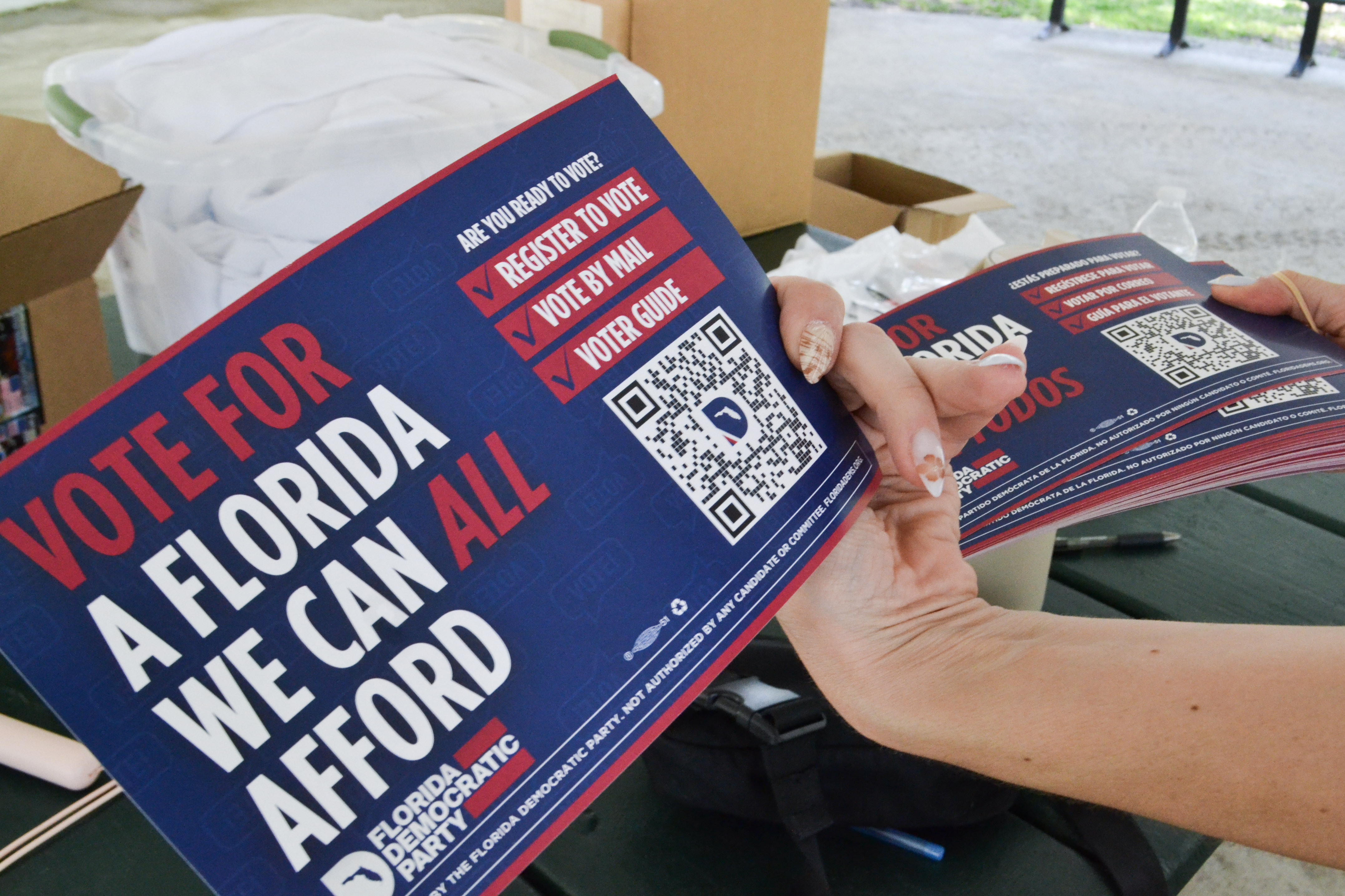 A hand holds up a pamphlet that reads, "Vote for a Florida we can all afford."