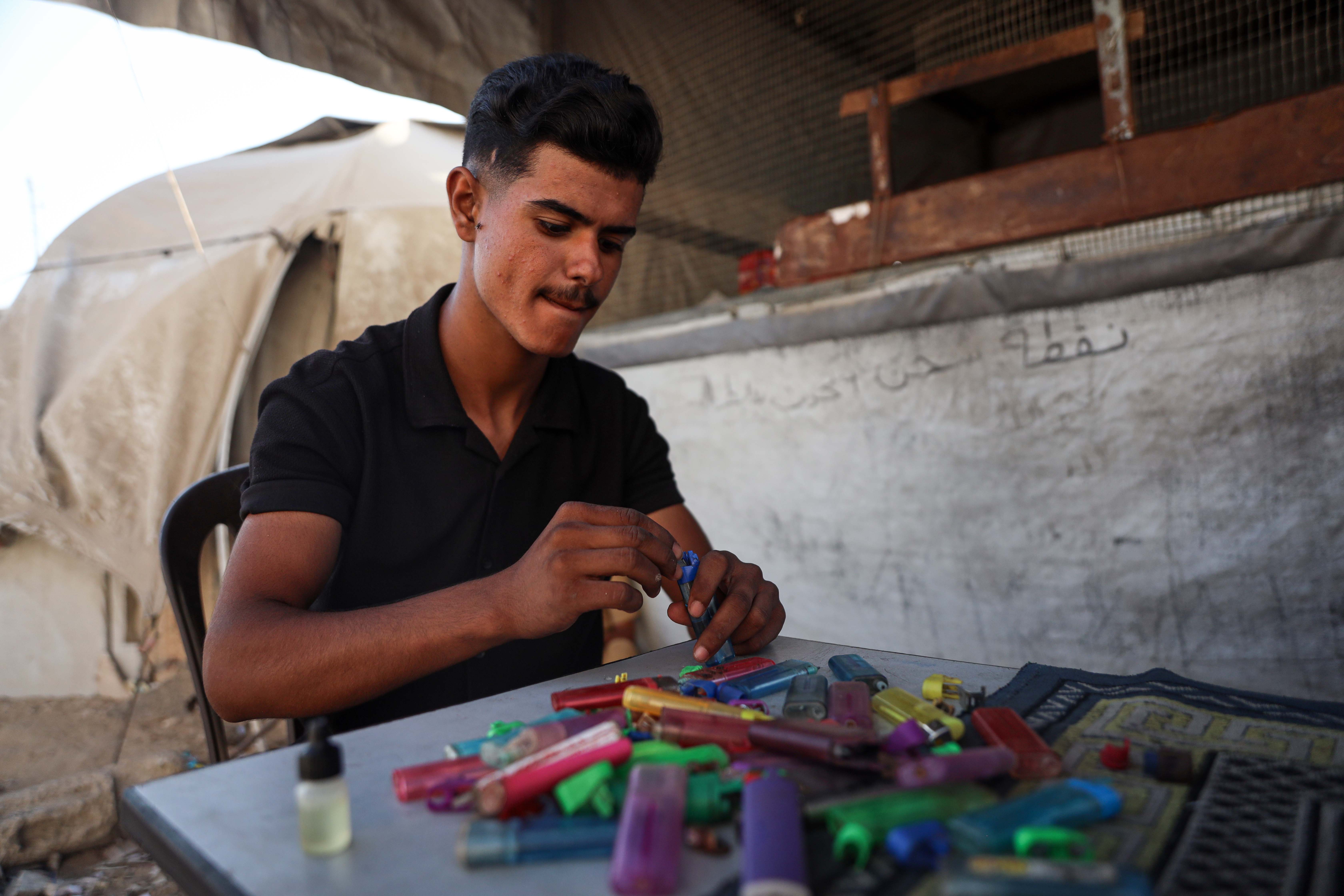 Tamer Al-Shawish, 24, repairs lighters at a small stall in a trade that emerged during the war [Abdelhakim Abu Riash/ Al Jazeera]