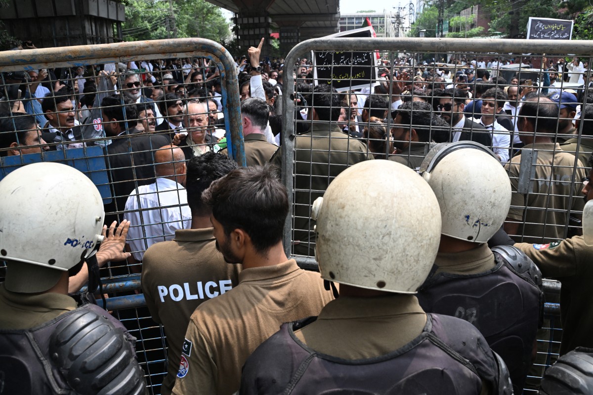 Police personnel restrict Pakistan Tehreek-e-Insaf (PTI) party supporters as they stage a protest demanding the release of their jailed leader and the country's former Prime Minister Imran Khan, in Lahore