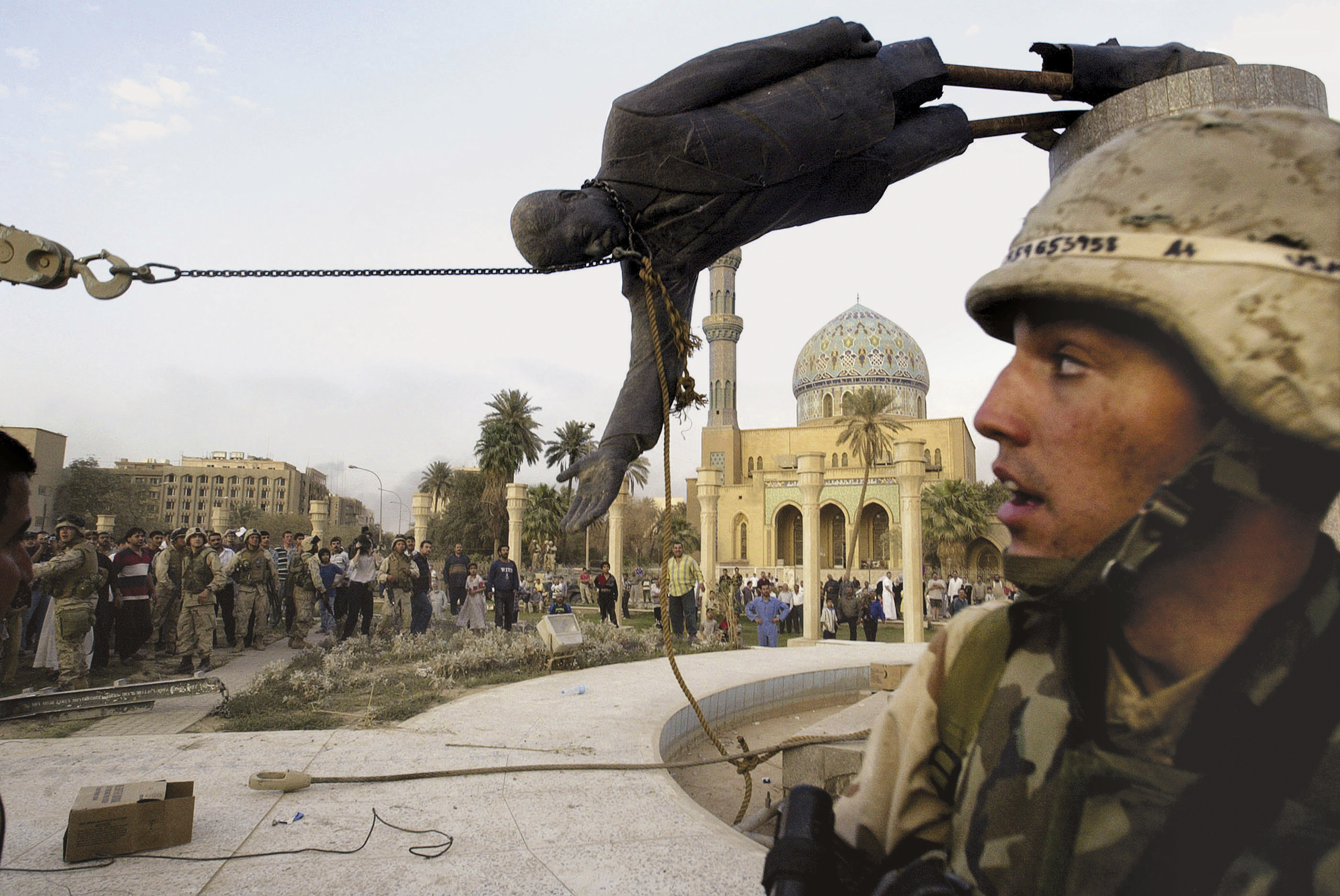 Iraqi civilians and US soldiers pull down a statue of former leader Saddam Hussein in downtown Baghdad, Iraq, on April 9, 2003