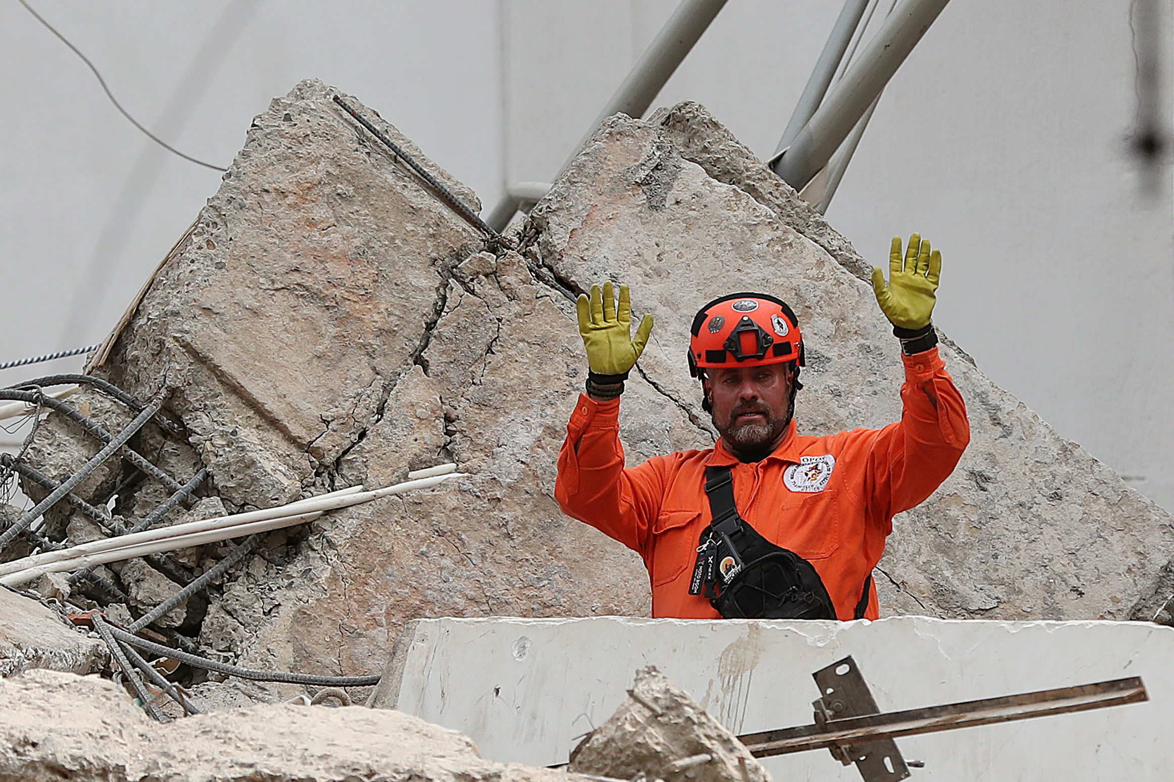 A rescue worker gestures while searching through rubble.