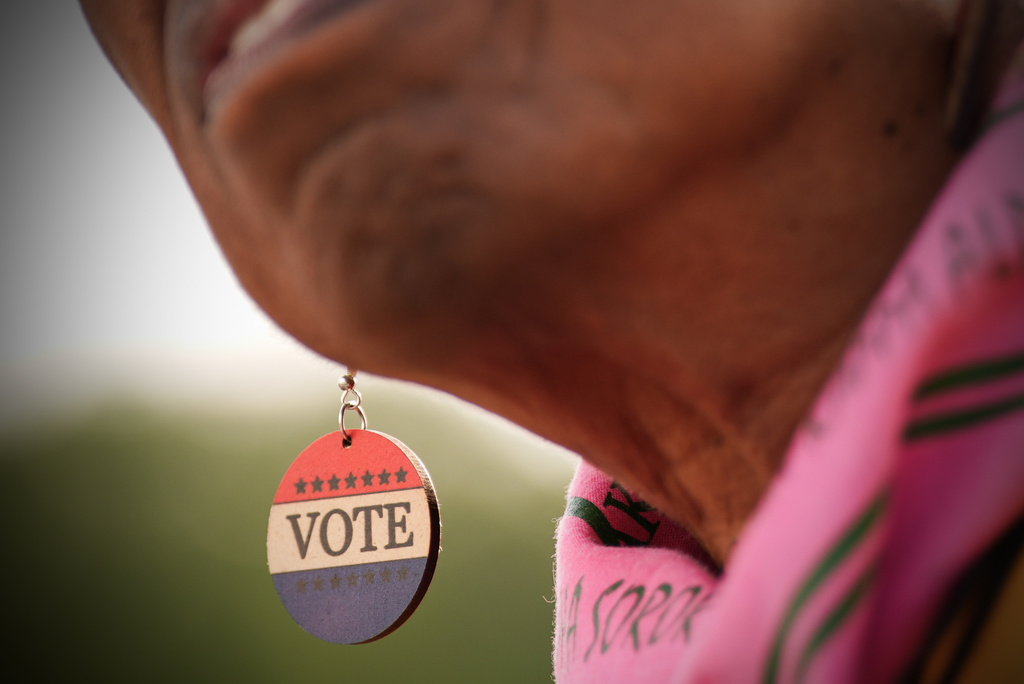 a woman with earrings reading 'vote'