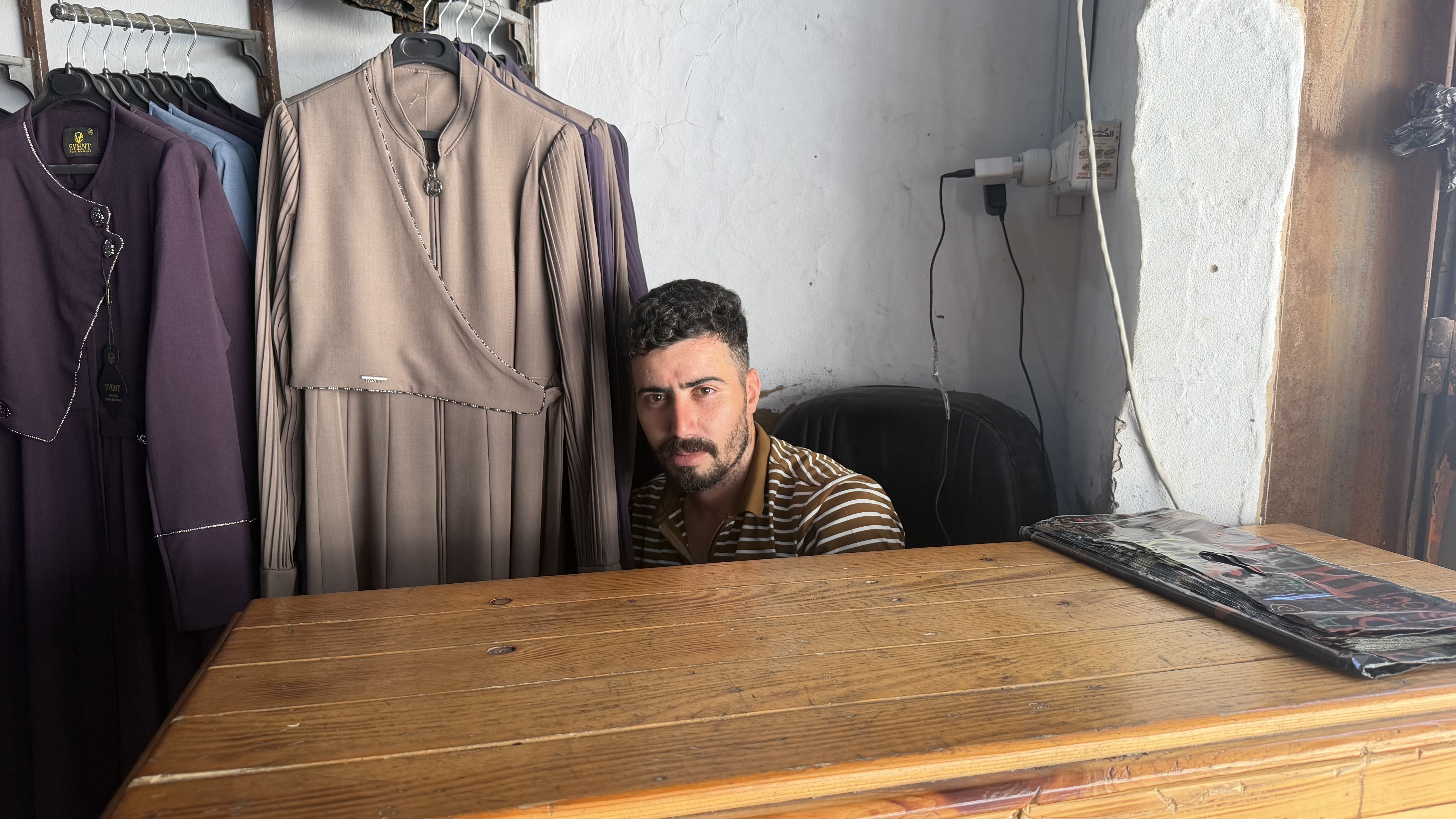 Firas Zaqloul sits in a clothing store trying to figure out a way to pay for his items because the seller won’t accept his cash