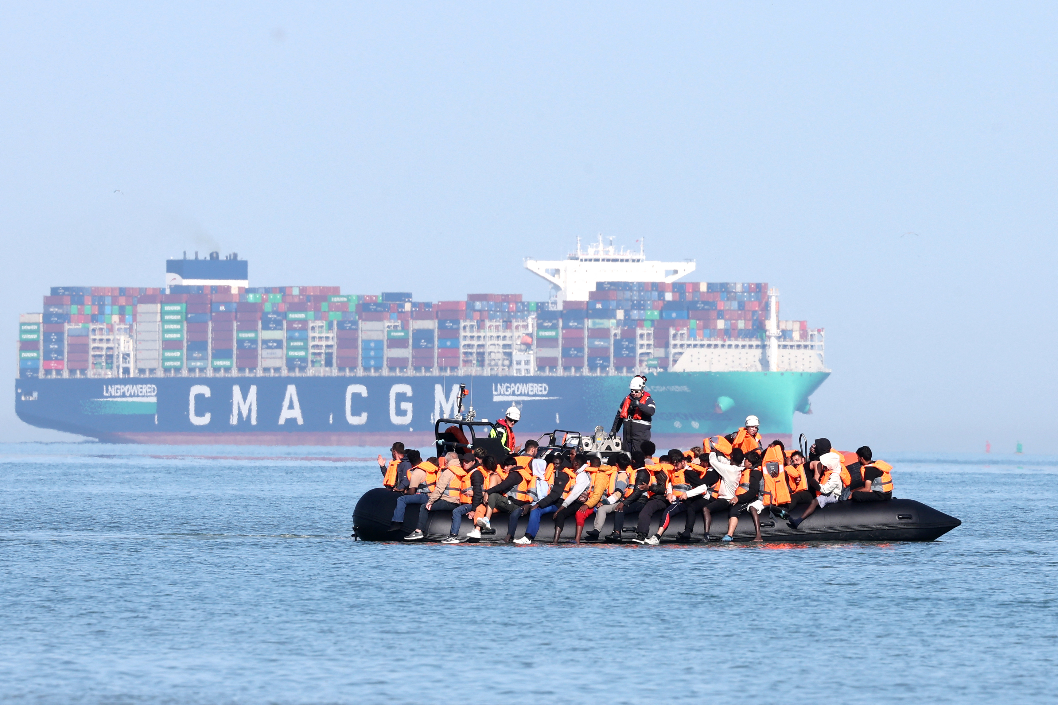 People on board a smugglers' boat at sea near a ship.