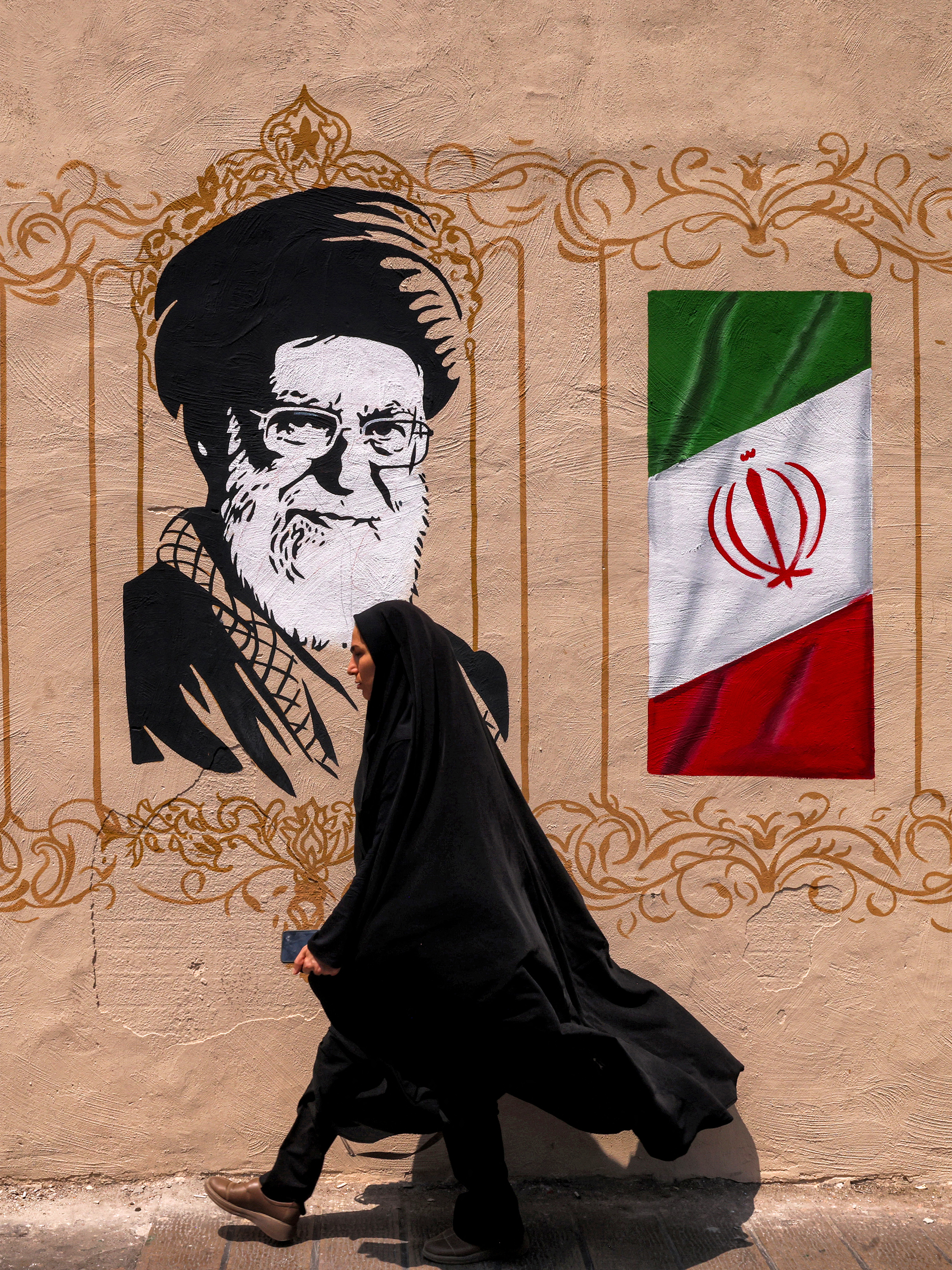 A woman walks past a mural depicting Iran's late supreme leader Ali Khamenei at Valiasr Square in central Tehran on August 8, 2026.