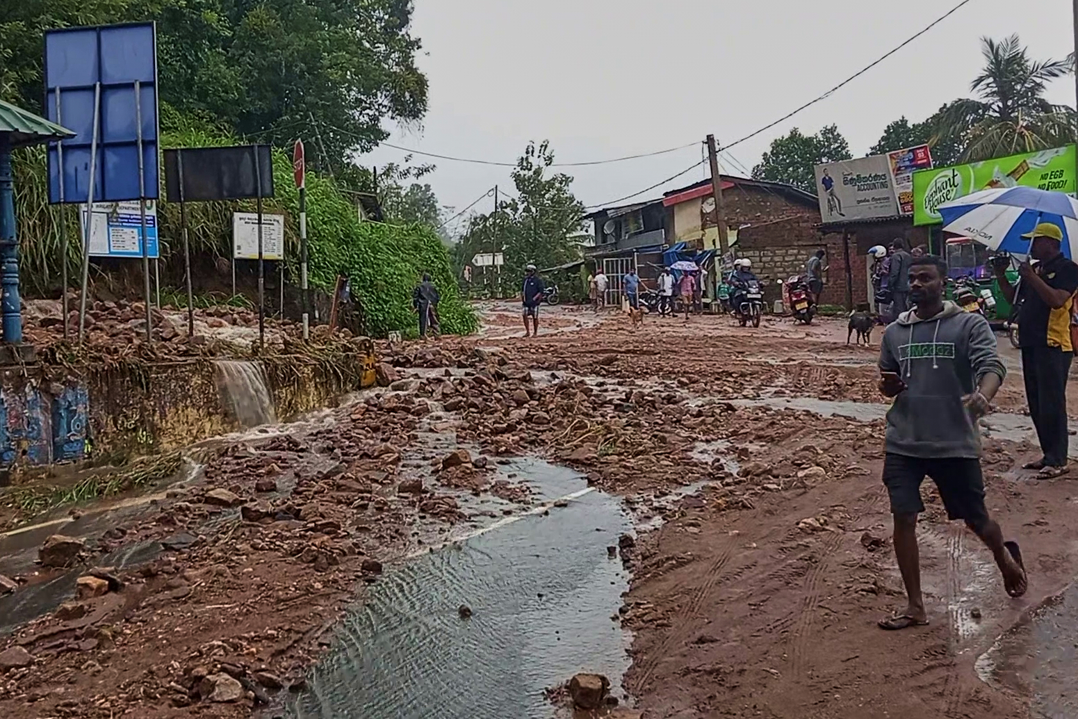 People walk across a mud covered road following heavy rain in Nawalapitiya, Sri Lanka, Tuesday, Aug. 4, 2026. (AP Photo)