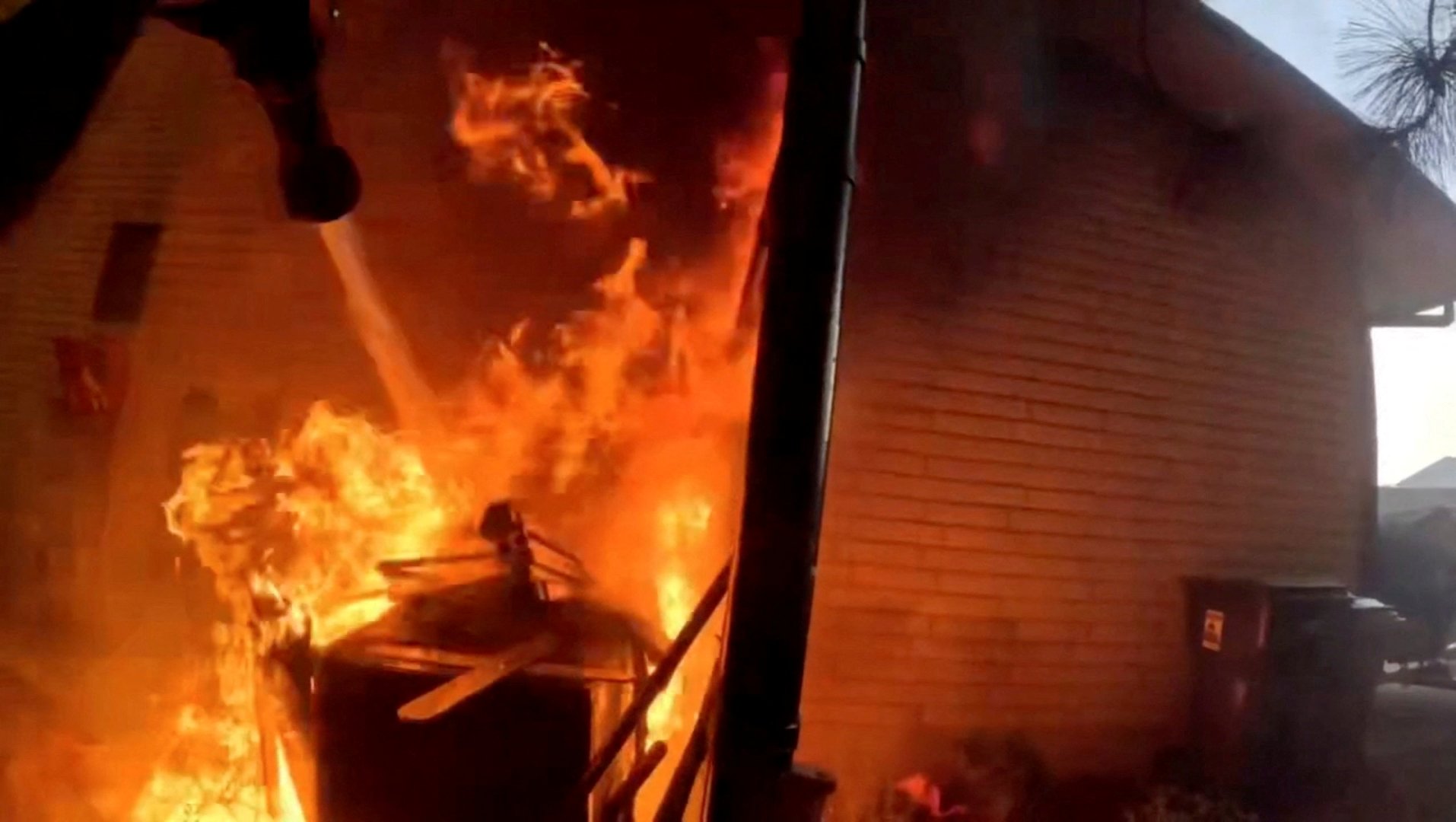 A firefighter works to put out a fire at a home as a wildfire burns in Spokane County, Washington, U.S., August 1, 2026, in this still image taken from bodycam video. [Spokane County Fire District 8 Firefighters Local 3711/Handout via REUTERS]