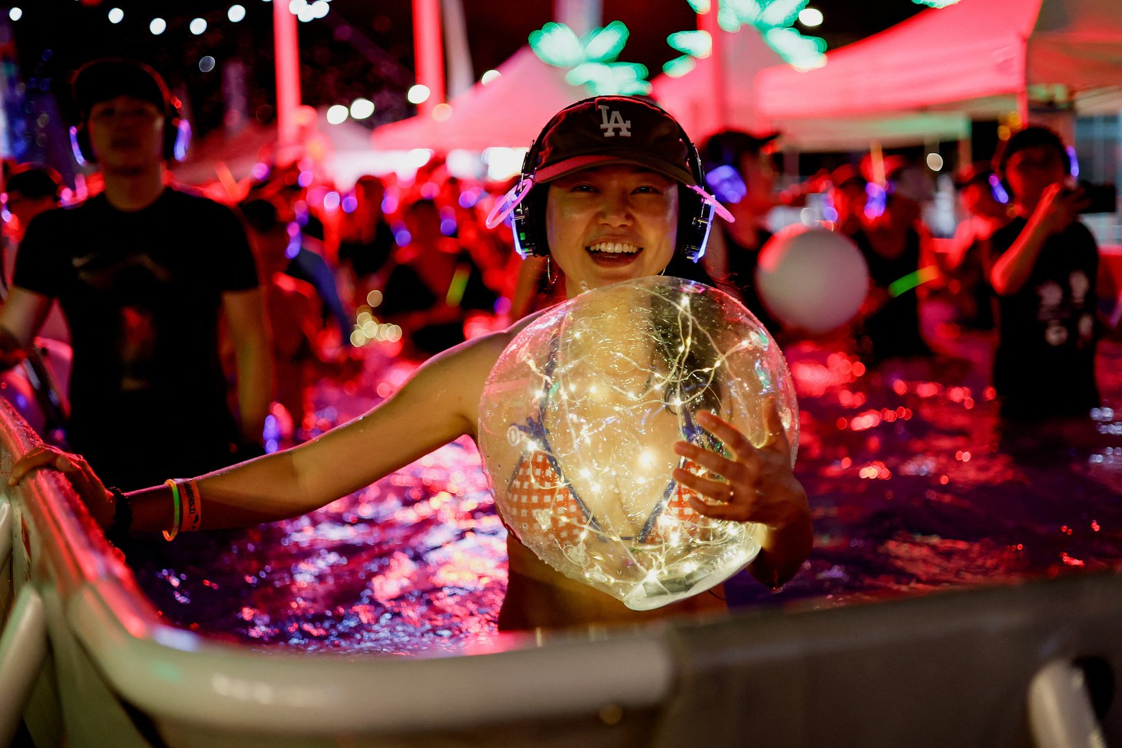A participant holds an illuminated ball while taking part in a "Silent Evening Pool Party" at Gwanghwamun Square amid a heatwave in Seoul, South Korea on Aug. 7, 2026. [Kim Soo-hyeon/Reuters]