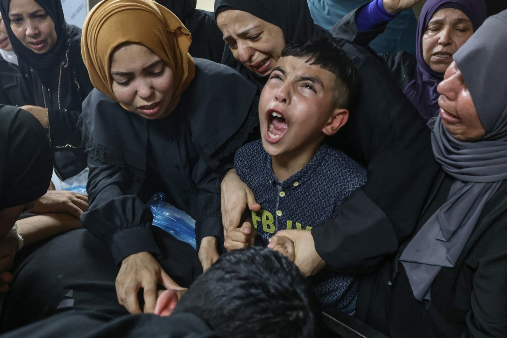 Mohamed (C), brother of 14-year-old Palestinian Islam Ajouri, grieves with his relatives over the body of his sibling at Rafidia Hospital in Nablus in the Israeli-occupied West Bank, on August 23, 2026, after he was allgedly killed earlier in the day by Israeli army gunfire at the nearby Askar refugee camp, according to the Palestinian health ministry. [Photo by JAAFAR ASHTIYEH / AFP]